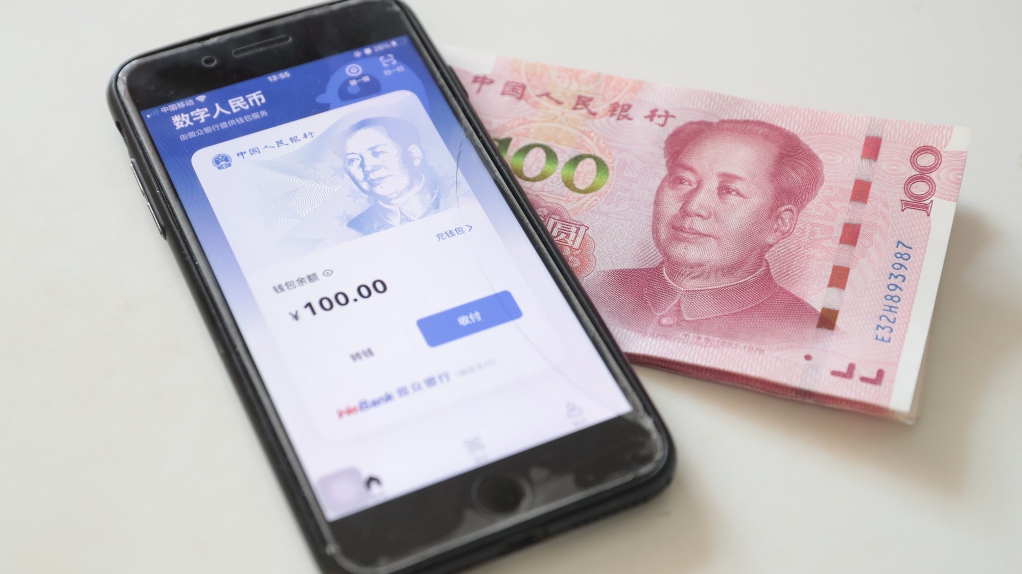 epa09669043 A view shows e-CNY digital wallet on a mobile phone beside Chinese paper currency, in Beijing, China, 06 January 2022. China has launched a smartphone app for making payments and transfers with the digital yuan the e-CNY app became available on app distribution platforms for Android and iOS users in China on 04 January 2022.  EPA/WU HONG