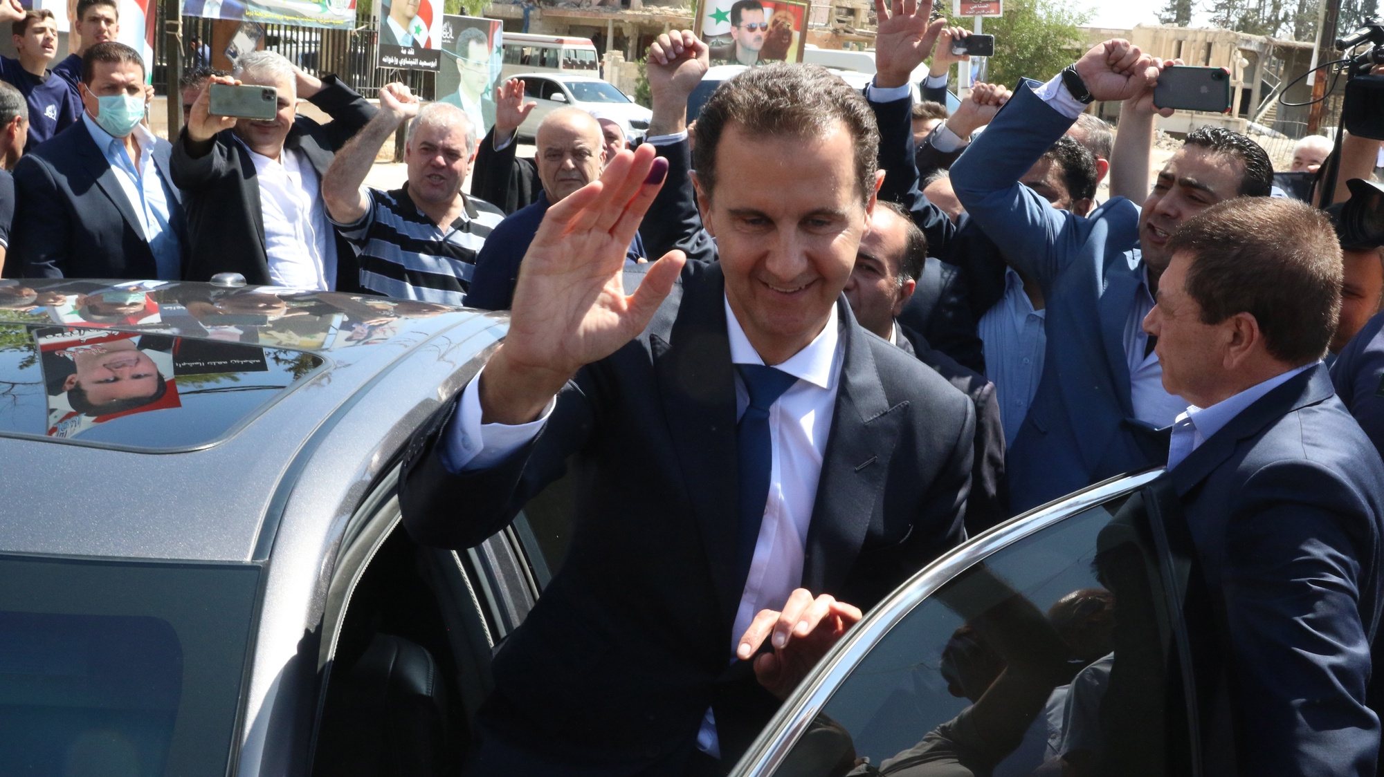 epa09623541 Syrian President Bashar al-Assad waves at supporters as he leaves a polling station in Duma city, Syria, 26 May 2021. The city was liberated by the Syrian army in 2018 after driving rebels out. Syrians will choose one out of three candidates, including Assad, for the post of President of the Syrian Arab Republic. The number of eligible voters registered inside and outside Syria has reached more than 18 million.  EPA/YOUSSEF BADAWI