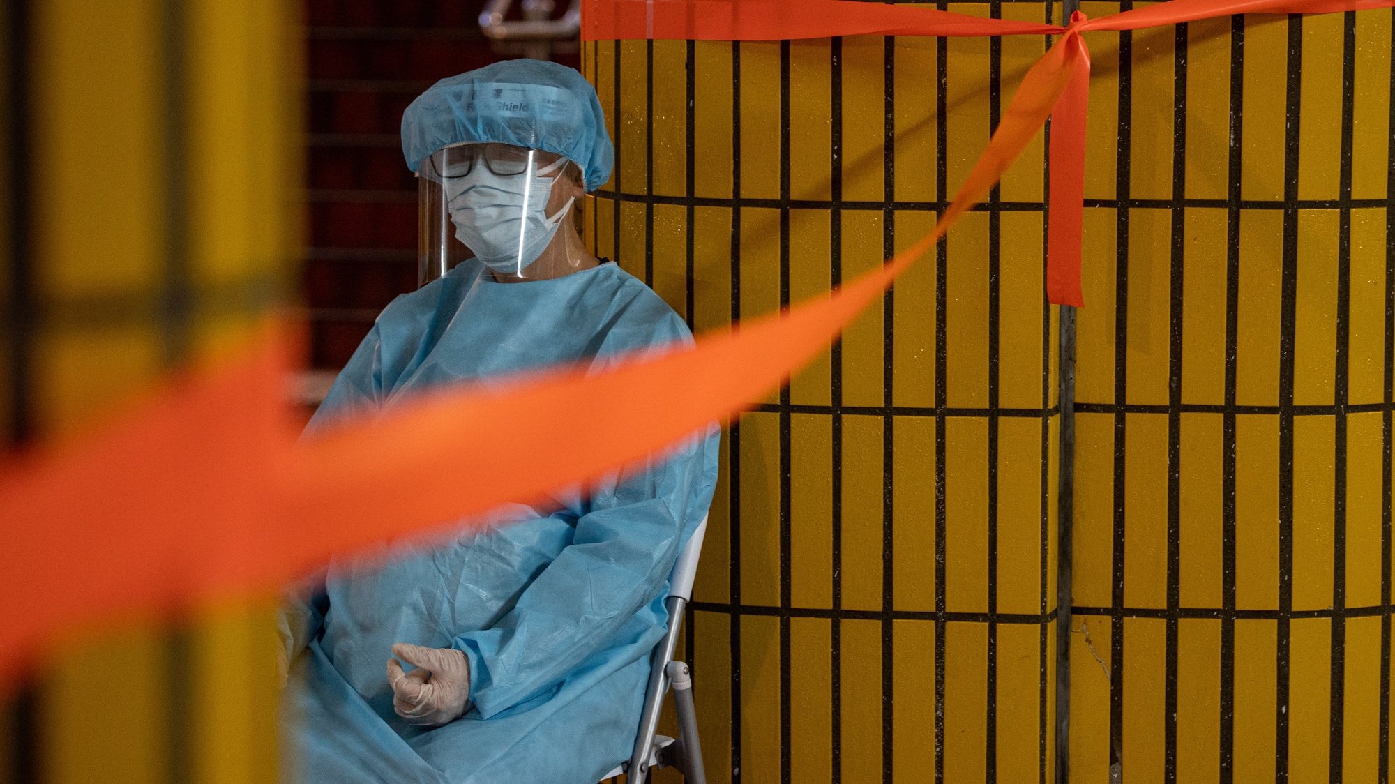 epa09848626 A health worker sits outside of a building under lockdown in Hong Kong, China, 25 March 2022. Starting from April 2022, the government will distribute kits with rapid COVID-19 tests, KN95 masks to 3 million households.  EPA/JEROME FAVRE