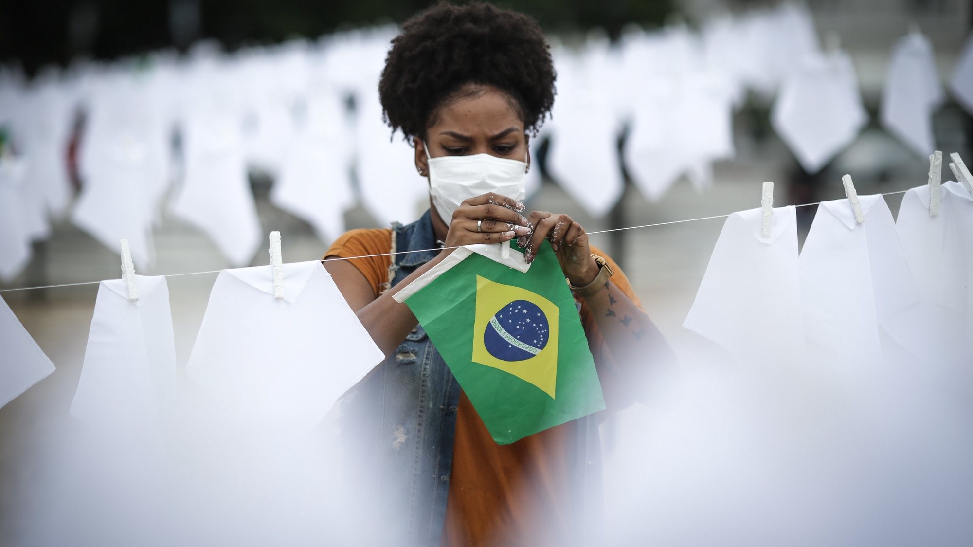 epa09513281 A volunteer helps to hang white handkerchiefs during a tribute to the thousands of fatalities of Covid-19 in Brazil, in Rio de Janeiro, Brazil, 08 October 2021. The NGO Rio de Paz held a protest on the Copacabana beach, in Rio de Janeiro, in which volunteers hung 600 white handkerchiefs in honor of the coronavirus victims in the country, whose number is now close to 600,000, as reported by official sources.  EPA/Andre Coelho