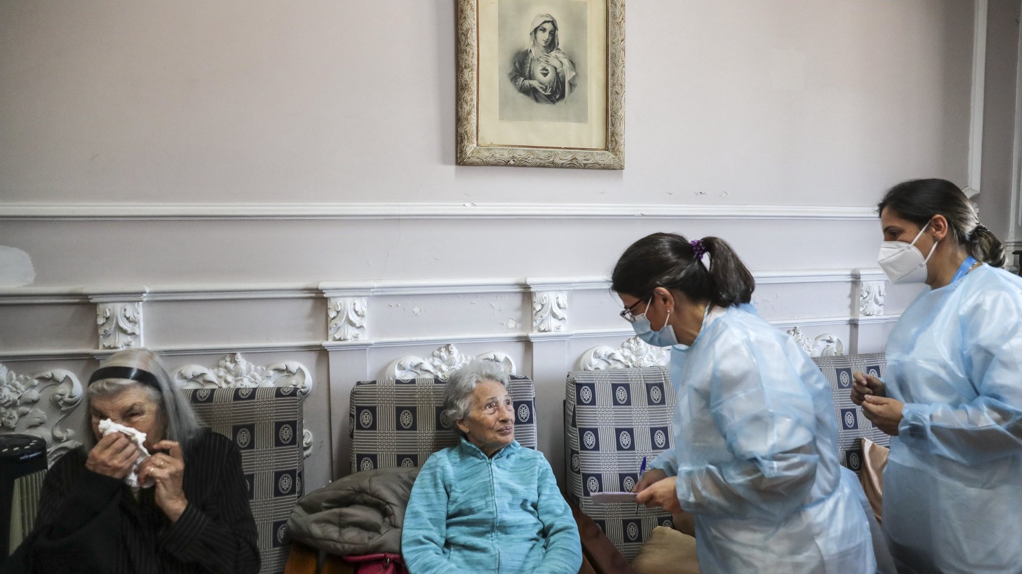 Uma utente de um lar de terceira idade conversa com enfermeiras momentos antes de ser vacinada com a quinta dose da vacina contra a covid-19, em Lisboa, 19 de maio de 2022. TIAGO PETINGA/LUSA