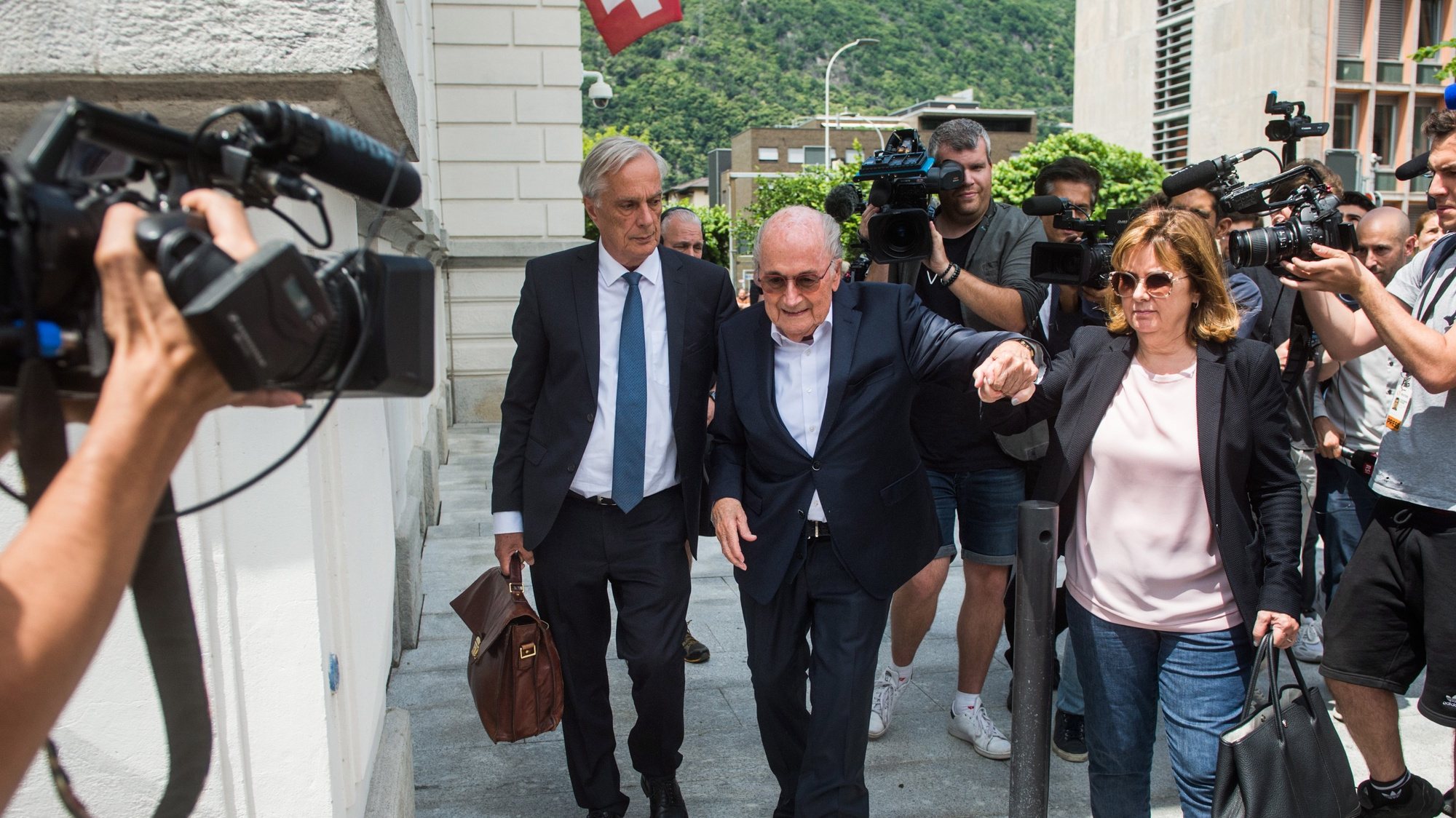 epa10001907 The former president of the World Football Association (Fifa), Joseph Blatter (C) with his daughter Corinne Blatter (R) and his lawyer Lorenz Erni (L), are surrounded by media representatives, as they leave the Swiss Federal Criminal Court after the first day of his trial, in Bellinzona, Switzerland, 08 June 2022. Blatter and the former president of the the European Football Association (Uefa), Michel Platini, stand trial before the Federal Criminal Court from 08 June, over a suspicious two-million payment. The Federal Prosecutor&#039;s Office accuses them of fraud. The defense speaks of a conspiracy.  EPA/ALESSANDRO CRINARI
