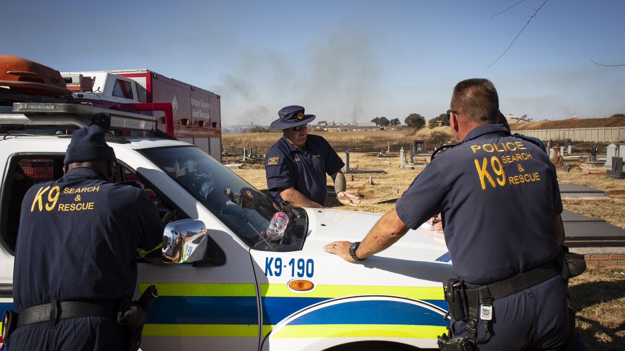 epa10018126 Members of the SAPS (South African Police Force) K9 unit discuss their approach during the ongoing search operation for a boy, Khayalethu Magadla (6), who fell into a water pipe six days ago, Soweto, Johannesburg , South Africa, 17 June 2022. Johannesburg EMS and SAPS police unites are continuing their search with robots being used in the underground waterways near where the boy went missing.  EPA/KIM LUDBROOK