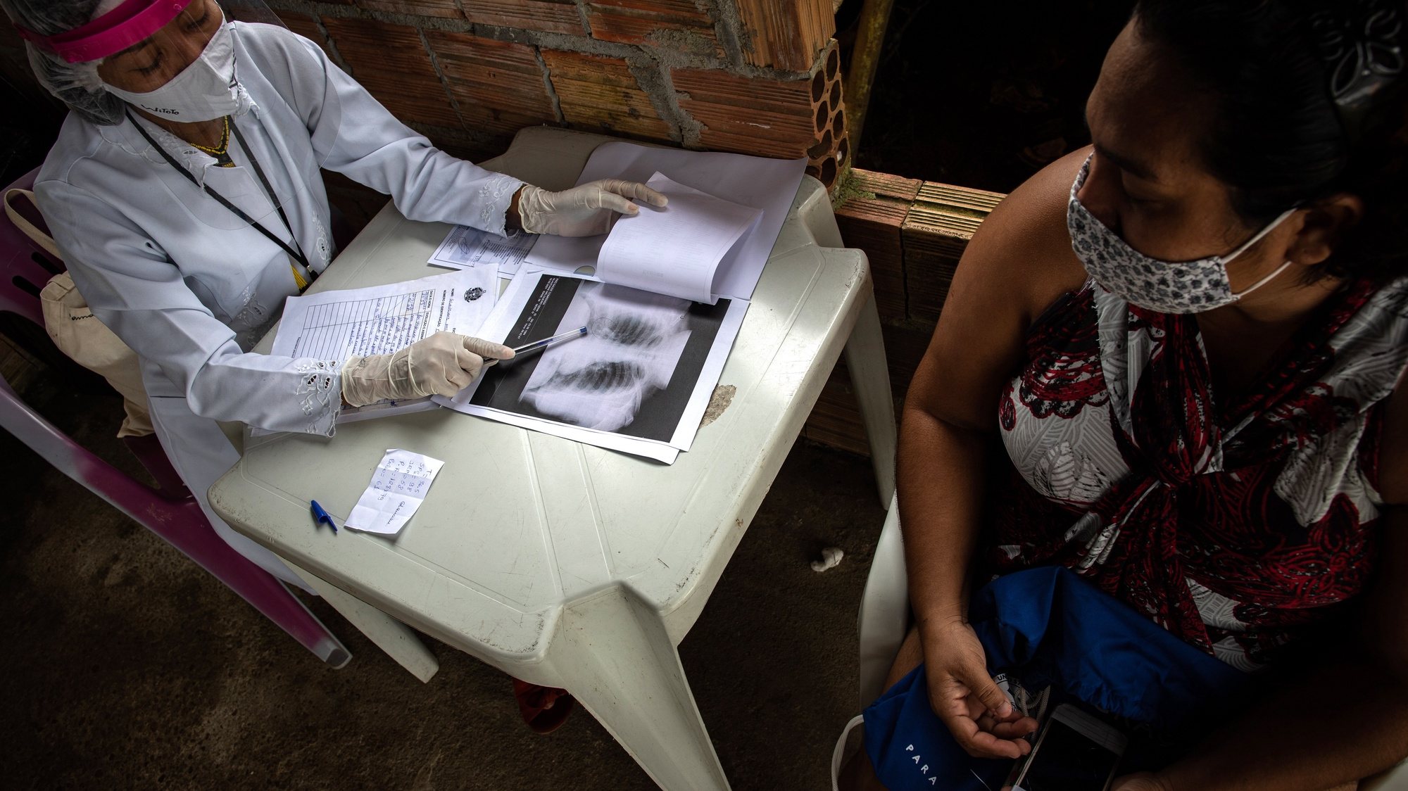 epa09007406 Nursing technician Vanda Ortega, 33, from Witoto people, reviews the lung imaging examination of the Covid-19 patient Glauciane Barbosa, 36, from the Bare people, at the Indigenous Support Unit, a field hospital built by native owners in Parque das Tribus, the only indigenous neighborhood in Manaus, Amazonas, Brazil, 11 February 2021 (issued 12 February 2021). The residents of an indigenous neighborhood in Manaus have erected a field hospital for the treatment of natives infected with the coronavirus in the midst of the oxygen lack crisis and the health collapse in the state.  EPA/RAPHAEL ALVES