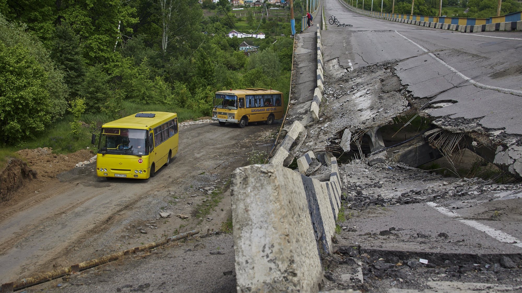 epa09987324 School buses carrying Ukrainian refugees drive past a damaged bridge near Kharkiv, Ukraine, 30 May 2022 (issued 31 May 2022). More than one thousand civilians were evacuated from both occupied and frontline territories. Russian troops entered Ukraine on 24 February, starting a conflict that has wrought havoc and triggered a humanitarian crisis. According to data released by the United Nations refugee agency UNHCR on 29 May, over 6.8 million people have fled Ukraine since Russian troops entered the country on 24 February 2022.  EPA/SERGEY KOZLOV