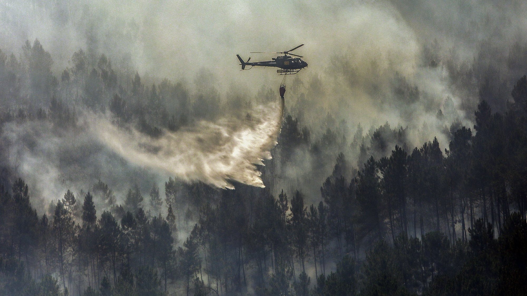 An helicopter drops water over a forest fire in the Beijames glacial valley, Covilha, Castelo Branco, Portugal, 09 August 2022. 580 operational, 205 vehicles and 13 airplane are fighting the forest fire. MIGUEL PEREIRA DA SILVA/LUSA