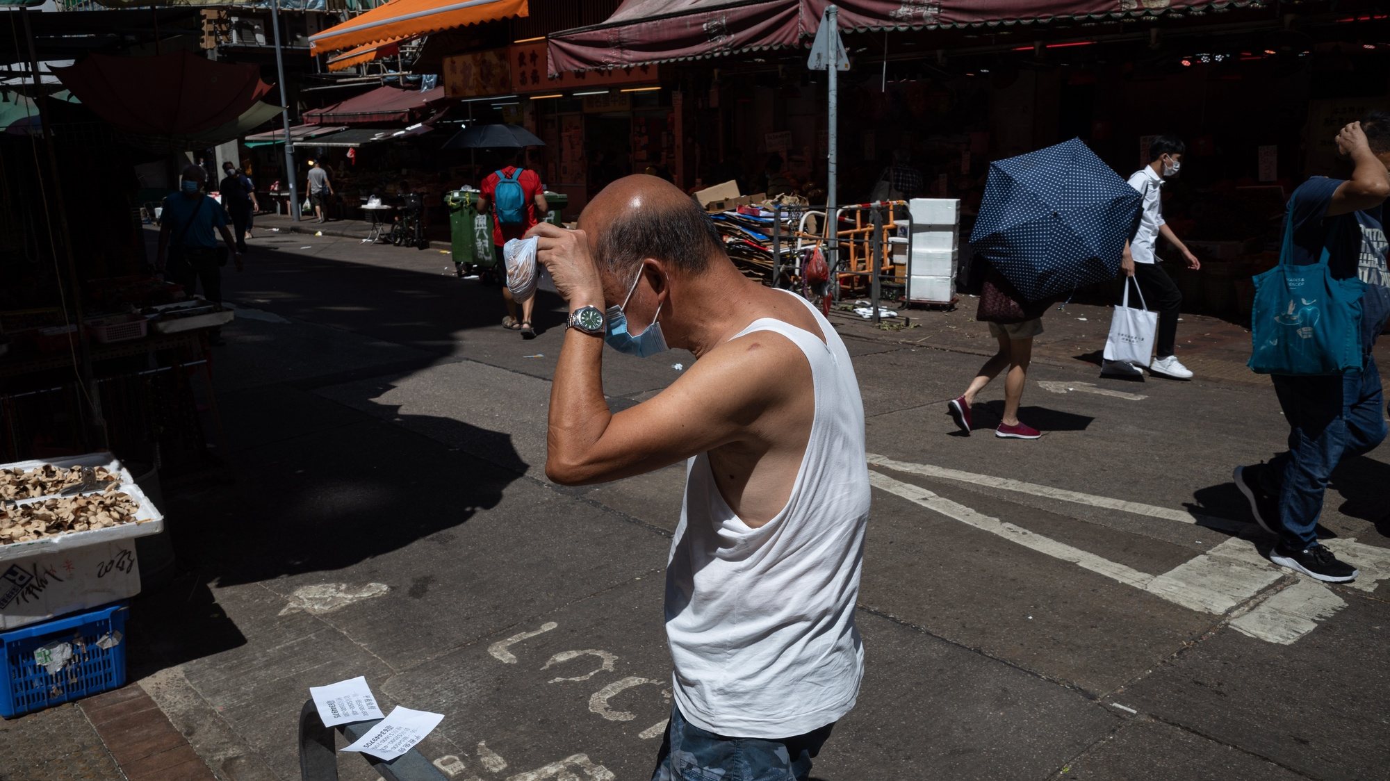 epa10091910 A man shields himself from the sun as he crosses a street in Hong Kong, China, 26 July 2022. The Observatory warned of persistently very hot and sunny weather for the rest of this week with the maximum temperature reaching 35 degrees or above in the urban areas, and a couple of degrees higher in the New Territories.  EPA/JEROME FAVRE