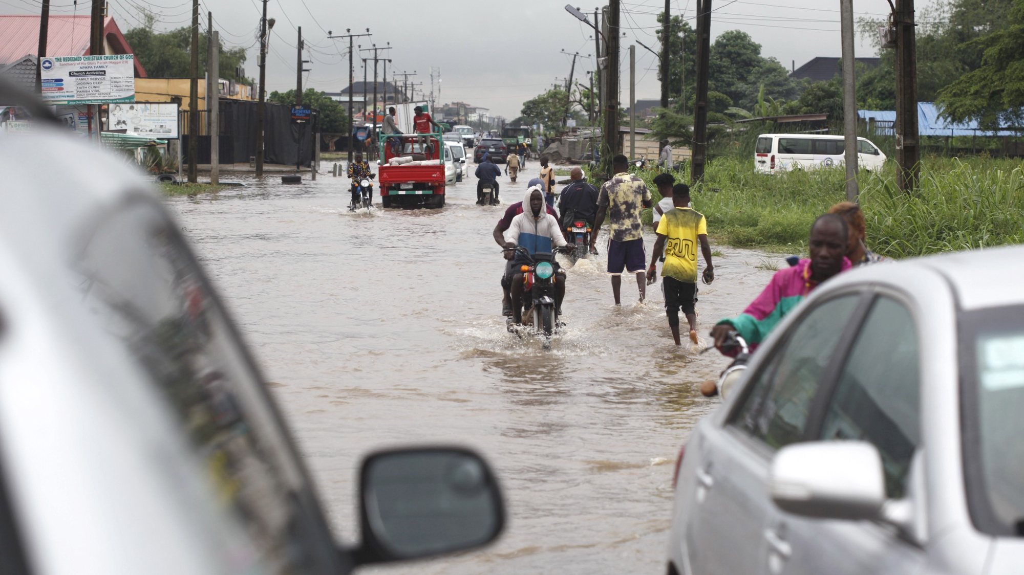 epa10180163 People wade through a flooded road after a rainfall in Lagos, Nigeria 12 September 2022. Flooding is a common phenomenon in Lagos with the impact on road and street trading.  EPA/Akintunde Akinleye