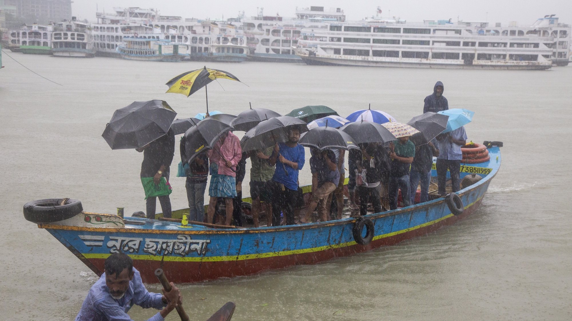 epa10262480 Bangladeshi passengers cross the Buriganga river as they hold umbrellas during a heavy rain and rough condition caused by cyclone Sitrang in Dhaka, Bangladesh, 24 October 2022. According to the Bangladesh Inland Water Transport Authority (BIWTA) and Bangladesh Meteorology Department, inland water transport has been suspended as the approaching cyclone Sitrang is expected to cross the South-Southwest part of Barishal and Chattogram district by 25 October. Bangladesh met office warned that the cyclonic storm may intensify further and turn into a severe cyclone.  EPA/MONIRUL ALAM