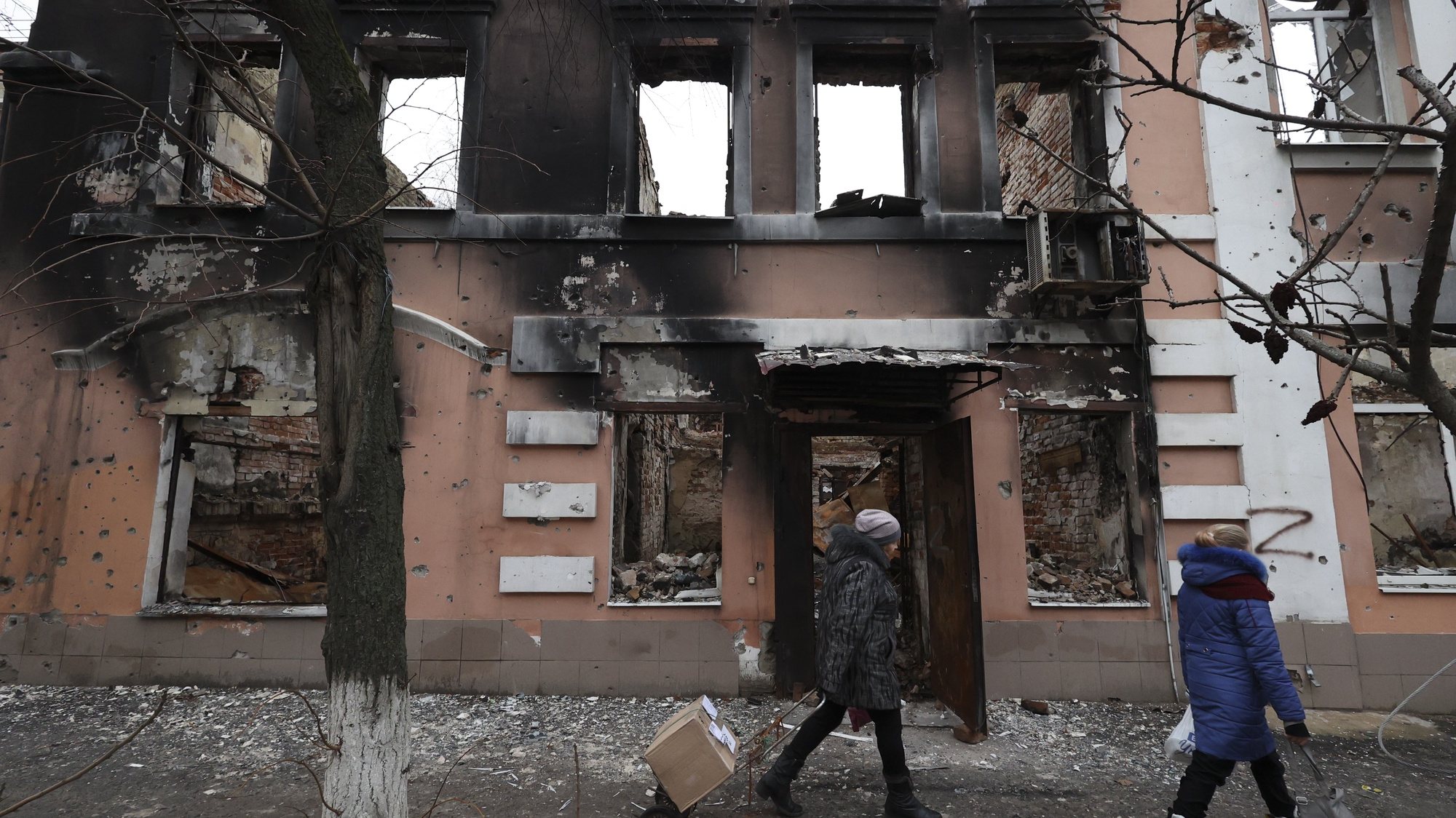 epa10376588 Local people walk past a destroyed building in Izium, Kharkiv region, Ukraine, 22 December 2022. Volunteers provide some 40 people with fresh hot meals per day. Russian troops on 24 February entered Ukrainian territory, starting a conflict that has provoked destruction and a humanitarian crisis.  EPA/SERGIY KOZLOV