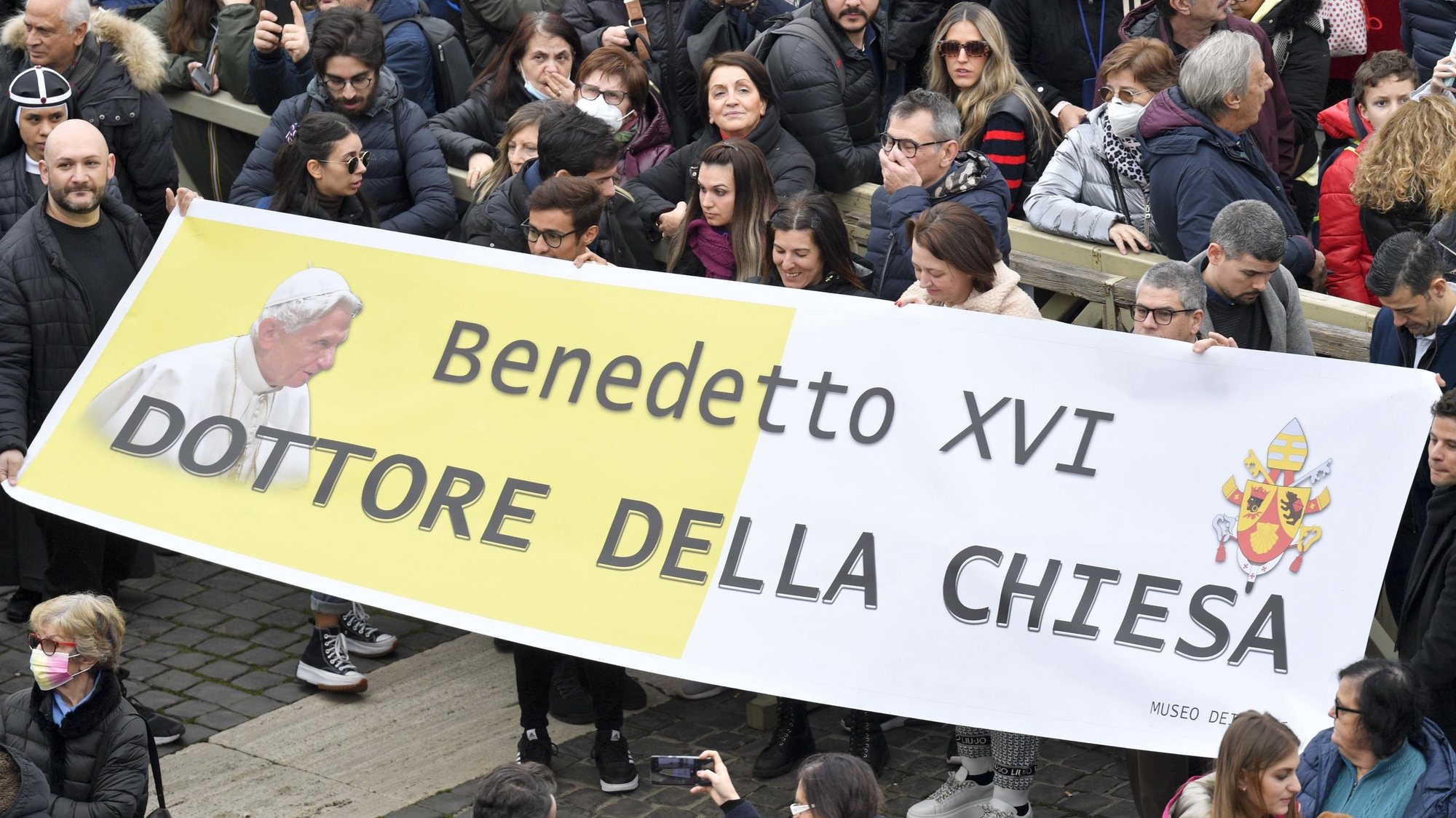 epa10392270 A handout picture provided by the Vatican Media shows faithfuls holding a banner reading &#039;Benedict XVI - Doctor of the Church&#039; in Saint Peter&#039;s Square as Pope Francis leads his Angelus prayer, in Vatican City, 06 January 2023. Pope Emeritus Benedict XVI died on 31 December 2022 at his Vatican residence, at the age 95. His funeral took place on 05 January.  EPA/VATICAN MEDIA HANDOUT  HANDOUT EDITORIAL USE ONLY/NO SALES