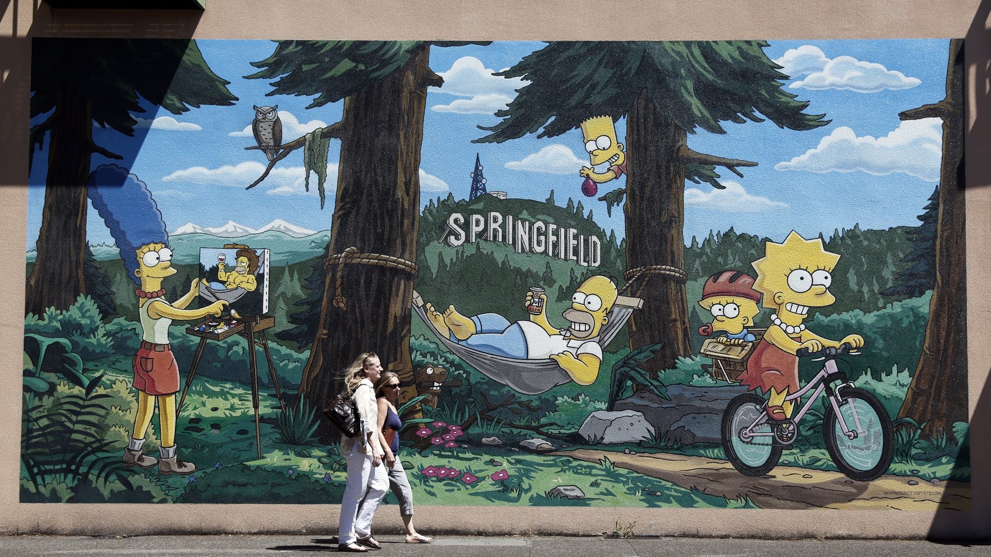epa10090346 Pedestrians walk by a mural by Old City Artists showing The Simpsons family in Springfield, Oregon, USA, 24 July 2022.  EPA/ETIENNE LAURENT