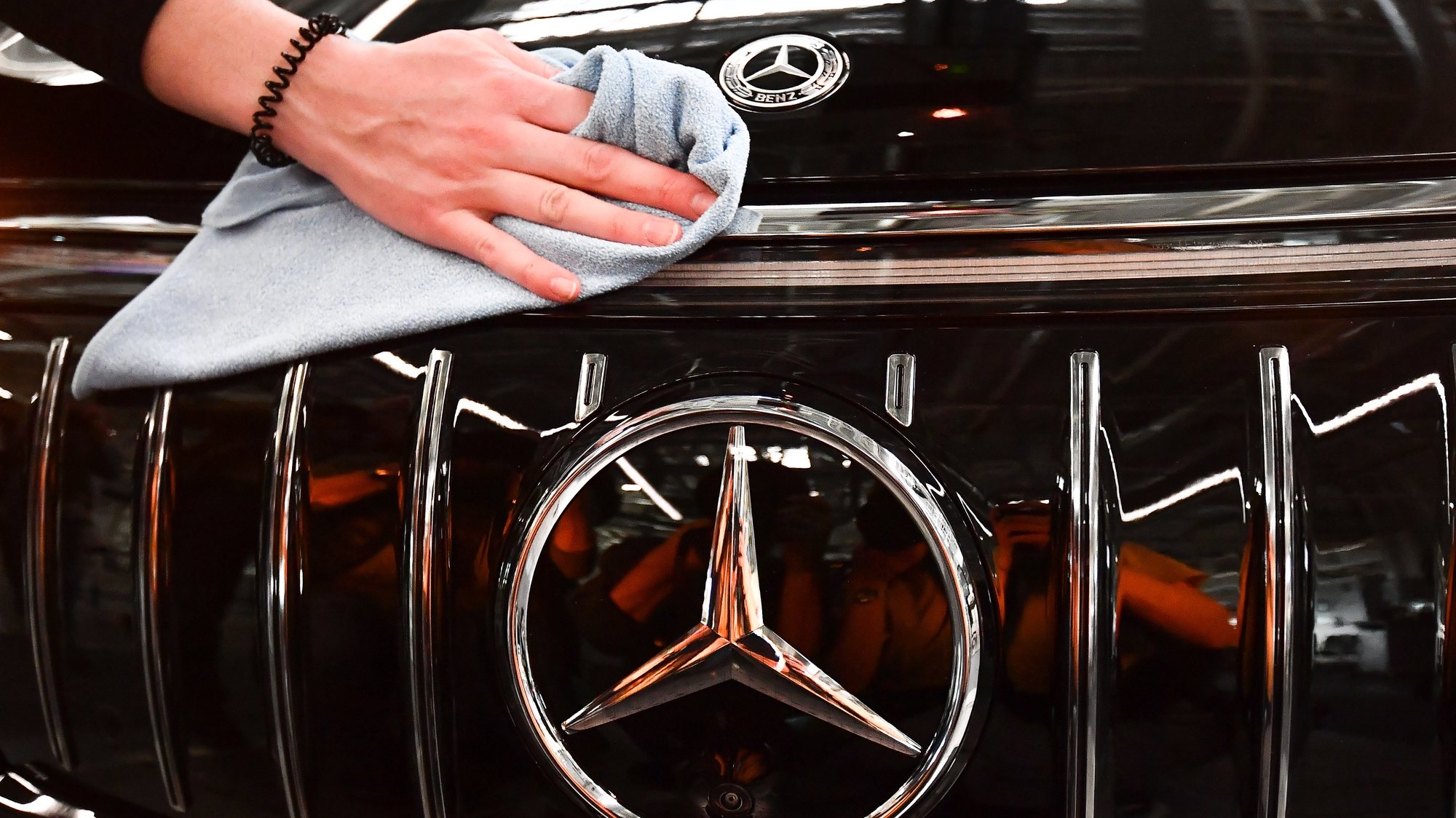epa10465195 Mercedes employee cleans the logo on a EQS car at the Mercedes-Benz plant in Sindelfingen, Germany, 13 February 2023.  EPA/ANNA SZILAGYI