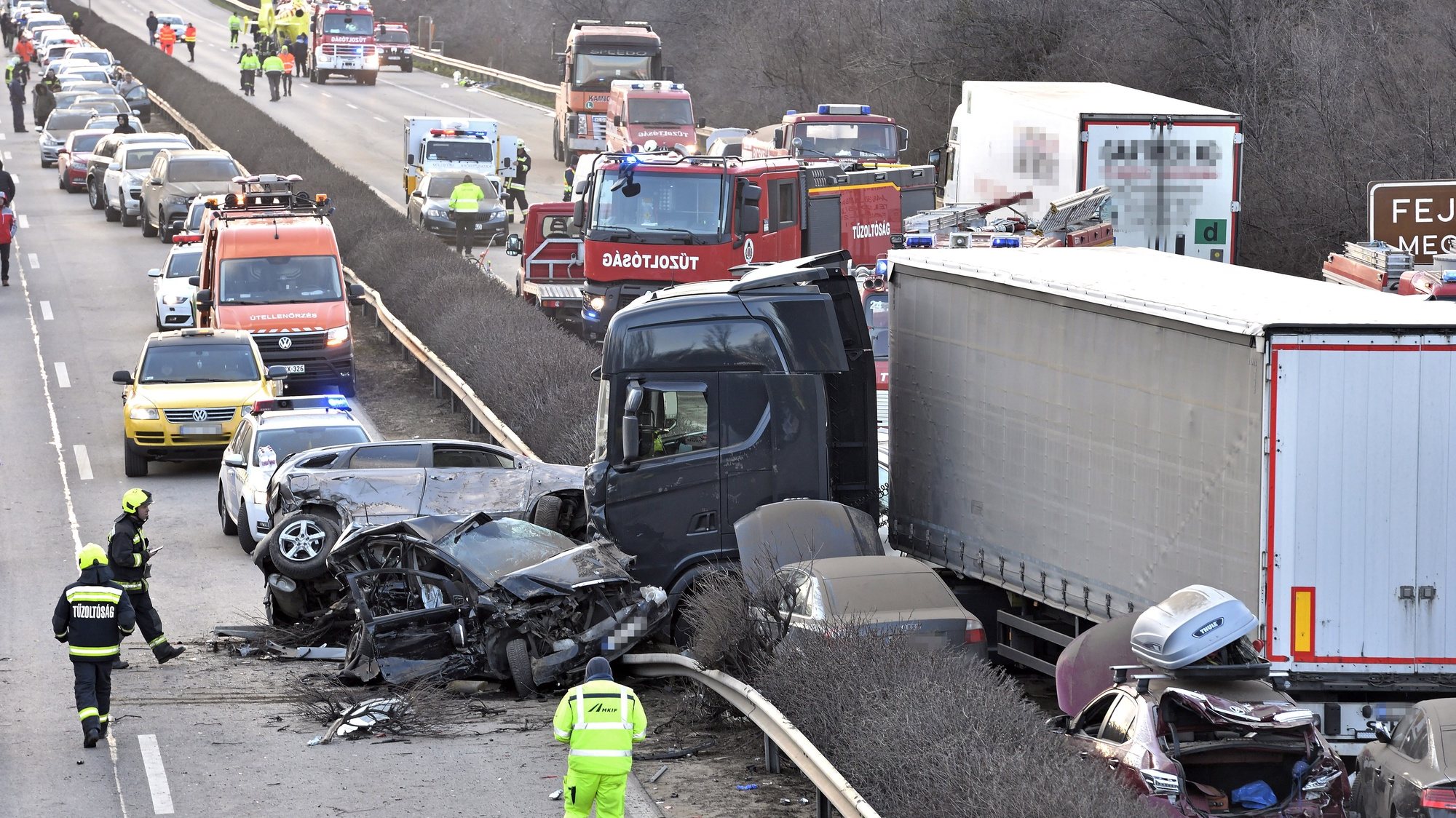 epa10515687 Rescuers work near wrecks and a truck after 5 trucks and 37 cars crashed on M1 motorway near Herceghalom, Hungary, 11 March 2023. Twenty-six persons were injured, six of them critically, and nineteen vehicles burnt out.  EPA/Peter Lakatos HUNGARY OUT