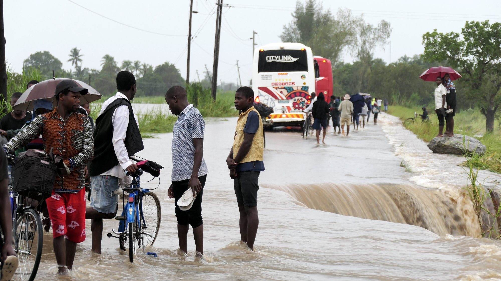 epa10522430 People walk on a road flooded by the River Bilila, Maputo, Mozambique, 14 March 2023. This is one of the longest lasting storms ever, after it formed at the beginning of February in the Asian seas, crossing the entire Indian Ocean to the east African coast. Until now 10 people have been killed by the storm according to official data.  EPA/ANDRÉ CATUEIRA