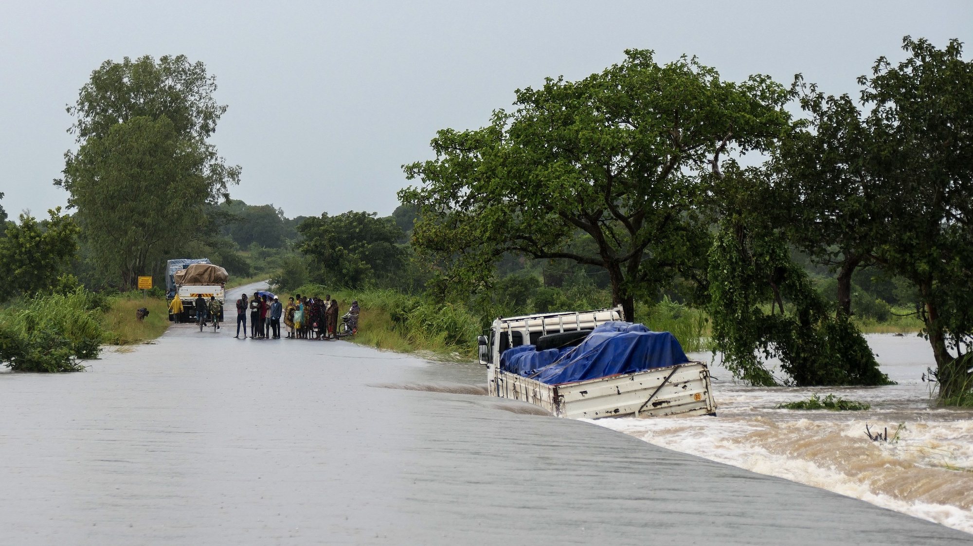 People walk on a road flooded by the River Bilila, Maputo, Mozambique, 14 March 2023. This is one of the longest lasting storms ever, after it formed at the beginning of February in the Asian seas, crossing the entire Indian Ocean to the east African coast. Until now 10 people have been killed by the storm accordind to official data. ANDRE CATUEIRA/LUSA