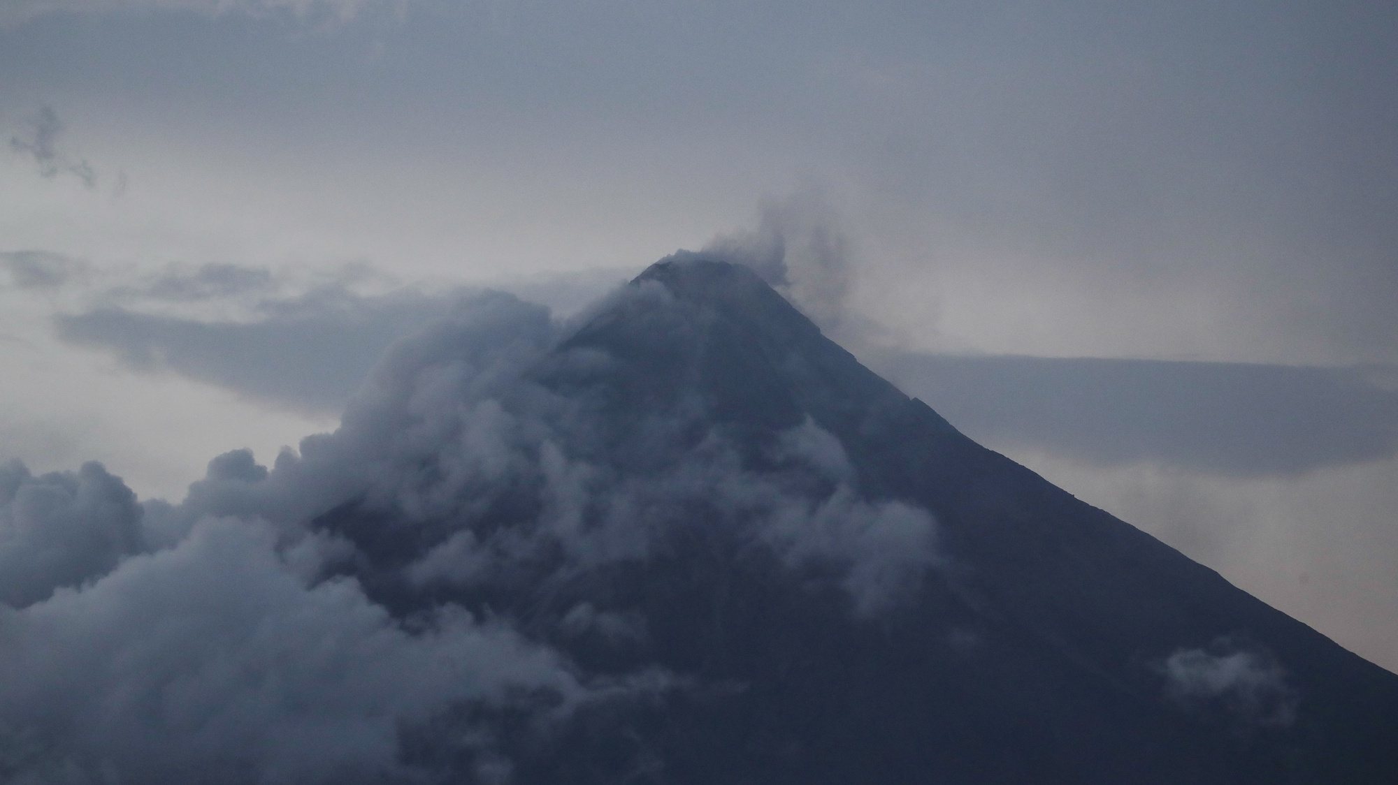 epa10681200 Mayon Volcano emits steam as seen from  Legazpi city, Albay province, Philippines, 09 June 2023. More than 20,000 residents living around Mayon volcano&#039;s danger zone are being evacuated in schools, gymnasiums, and tents amid impending eruption.  EPA/FRANCIS R. MALASIG