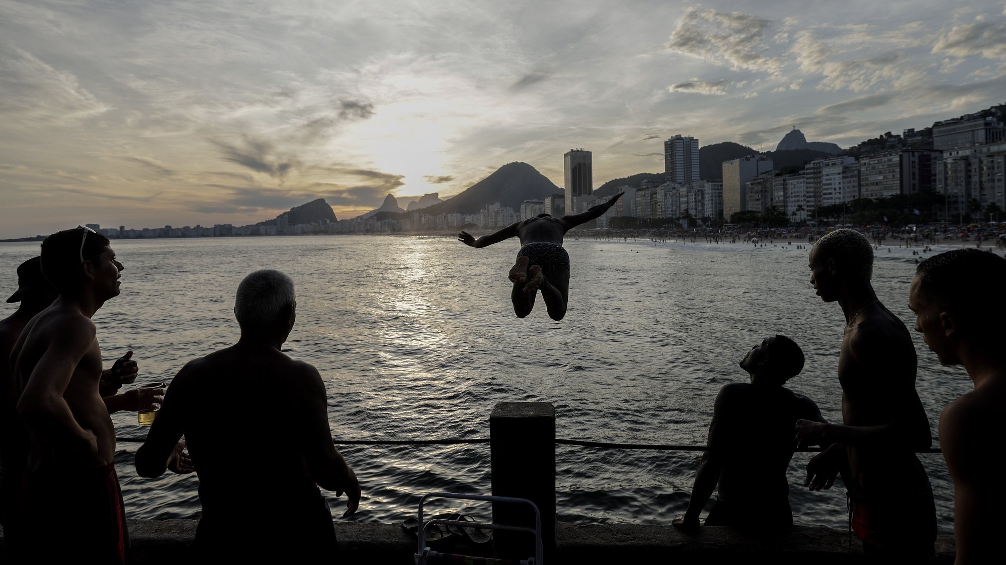 epa10424082 A man jumps into the sea at Leme beach in Rio de Janeiro, Brazil, 22 January 2023.  EPA/Antonio Lacerda