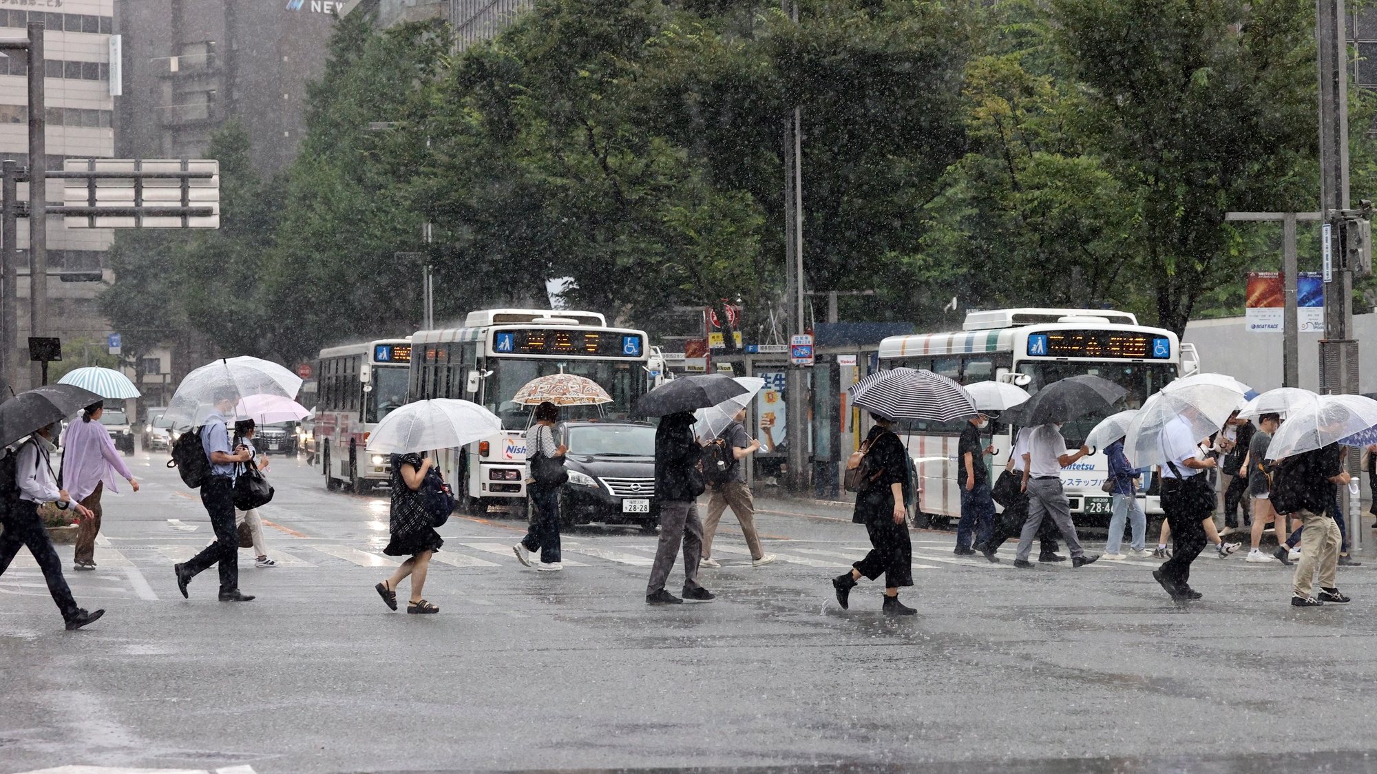 epa10736933 People cross a street under heavy rain in Fukuoka, southwestern Japan, 10 July 2023. The Japan Meteorological Agency issued the highest level of alert after heavy rainfall hit southwestern Japan. Landslides across the region caused the death of one person as three are still missing.  EPA/JIJI PRESS JAPAN OUT EDITORIAL USE ONLY/