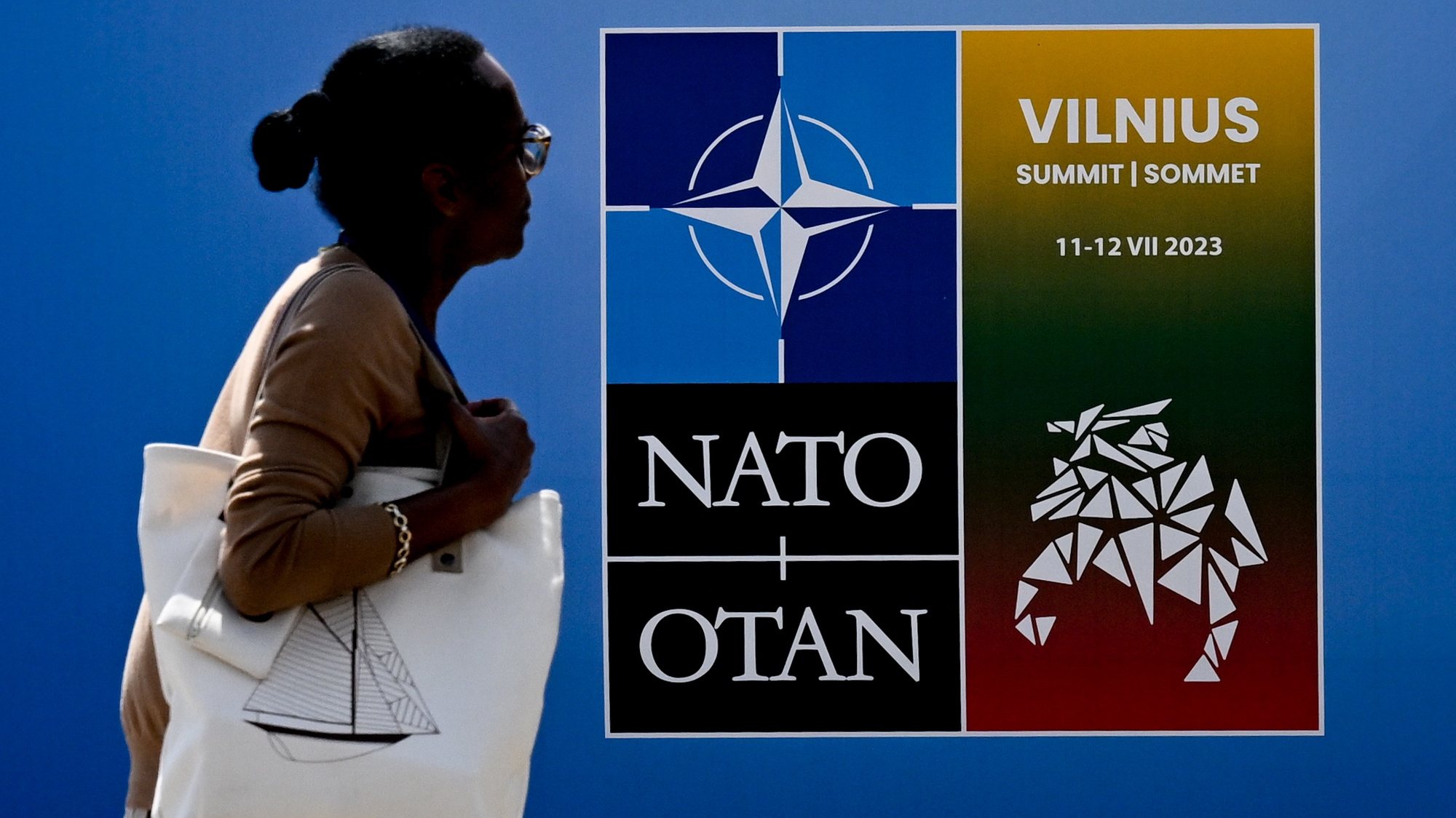 epaselect epa10735912 A woman passes by a NATO poster at the NATO summit venue in Vilnius, Lithuania, 09 July 2023. NATO Summit will take place in Vilnius on 11 and 12 July 2023.  EPA/FILIP SINGER