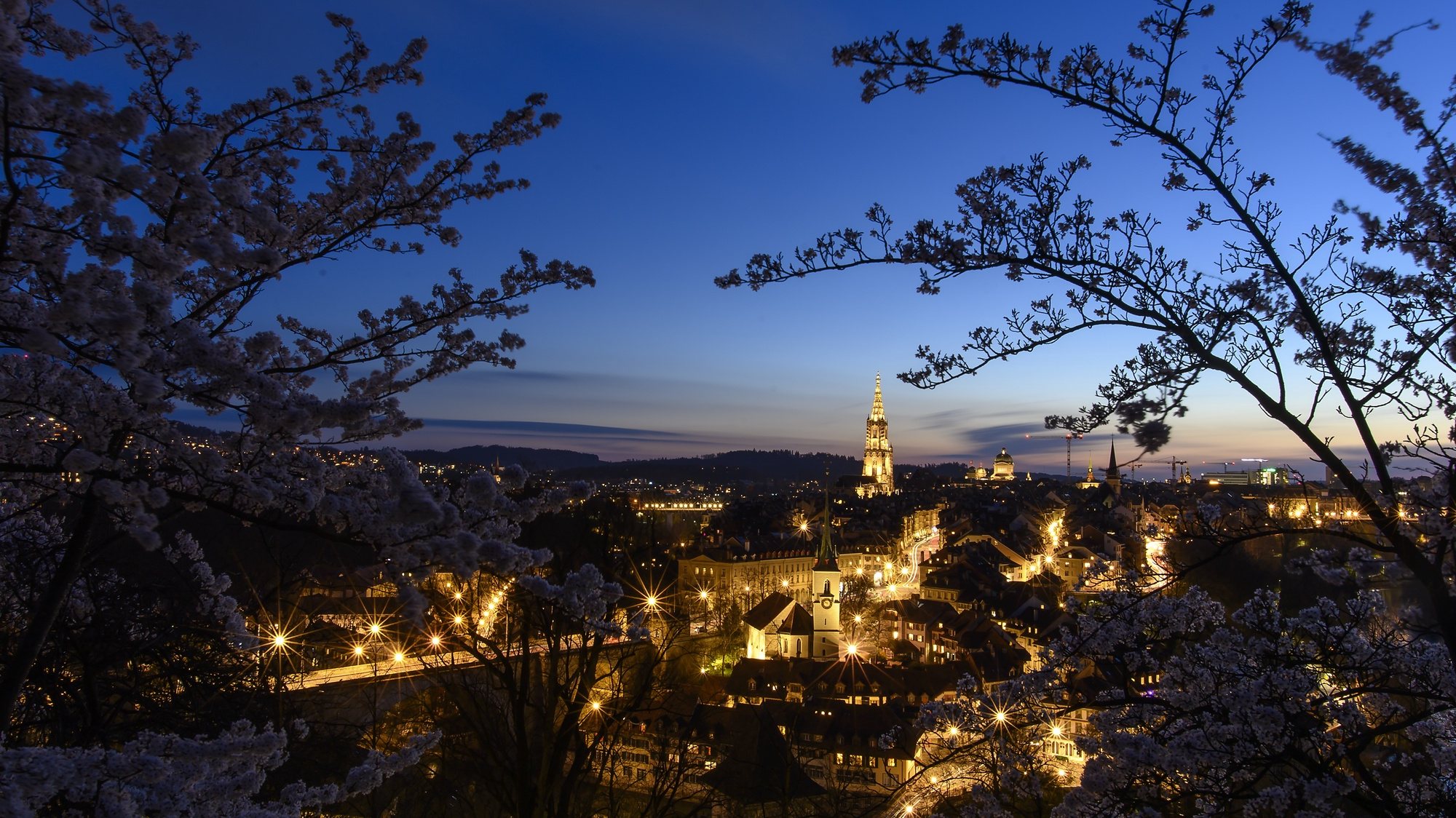 epa09114938 The City of Bern is seen between flowering cherry trees during a sunset from Rosengarten, Bern, Switzerland, 03 April 2021 (issued 04 April 2021).  EPA/ANTHONY ANEX
