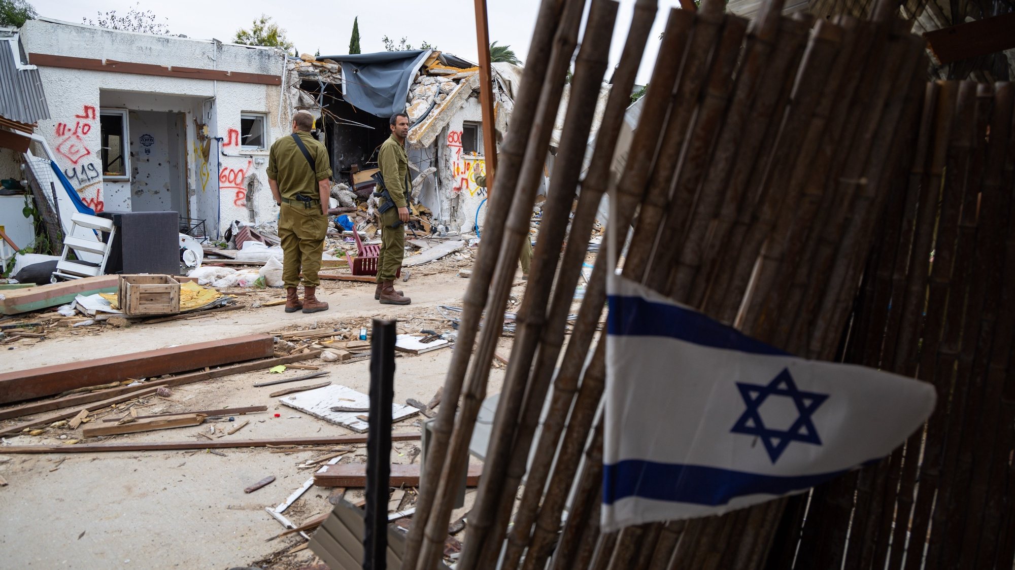 epa10989455 Israeli soldiers stand near damaged homes during a press visit at Kfar Aza Kibbutz, southern Israel, 22 November 2023. The kibbutz, located near the Gaza border, was the scene of an Hamas attack on 07 October which resulted in the deaths of dozens of Israelis. More than 12,700 Palestinians and at least 1,200 Israelis have been killed, according to the Israel Defense Forces (IDF) and the Palestinian health authority, since Hamas militants launched an attack against Israel from the Gaza Strip on 07 October, and the Israeli operations in Gaza and the West Bank which followed it.  EPA/CHRISTOPHE PETIT TESSON