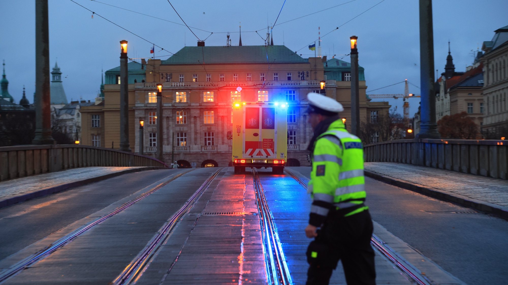 epa11039960 A Police officer stands guard as an ambulance rushes to the scene of a shooting in central Prague, 21 December 2023. According to Czech Police several people have been killed and &quot;dozens&quot; injured in an incident in the capital of the Czech Republic.  EPA/MARTIN DIVISEK
