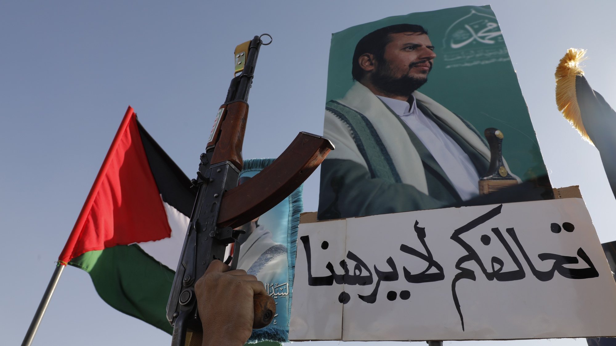 epa11041164 A man holds a gun next to a placard with a photo of top Houthi leader Abdul-Malik al-Houthi and a slogan reading in Arabic &#039;Your coalition does not intimidate us&#039; during a protest against the recently announced operation to safeguard trade and to protect ships in the Red Sea, in Sana&#039;a, Yemen, 22 December 2023. Thousands of people gathered at a square in the Houthis-controlled Sana&#039;a to protest against the coalition created recently by the United States and denounce the Israeli strikes on the Gaza Strip. On 18 December, the US Department of Defense announced a multinational operation to safeguard trade and to protect ships in the Red Sea amid the recent escalation in Houthi attacks originating from Yemen, according to a press release from the US Department of Defense. Thousands of Israelis and Palestinians have died since the militant group Hamas launched an unprecedented attack on Israel from the Gaza Strip on 07 October, and the Israeli strikes on the Palestinian enclave which followed it.  EPA/OSAMAH YAHYA