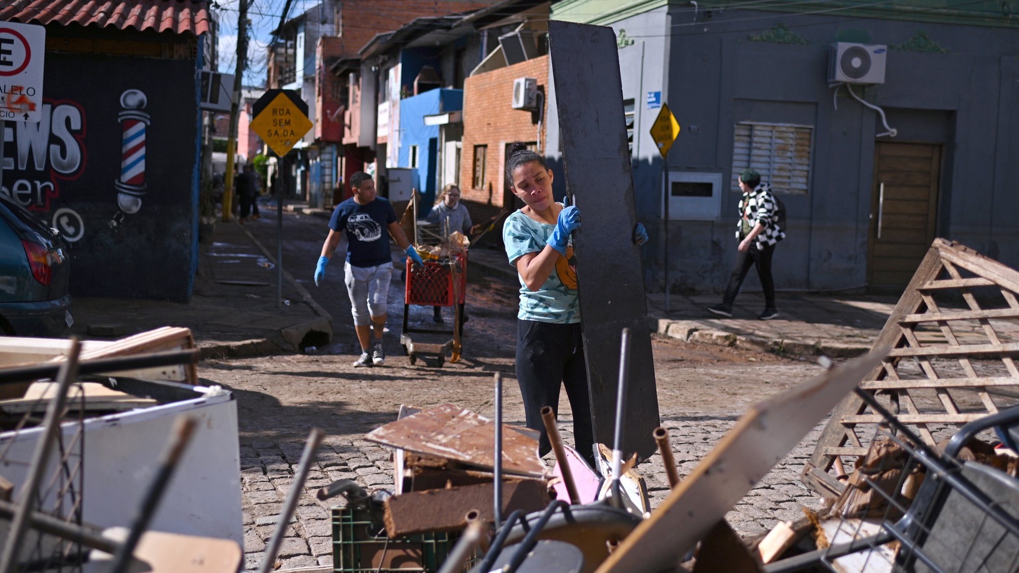epa11348631 Residents work to clean a street in an area where flood water levels have already receded in the Menino Deus neighborhood, in Porto Alegre, state of Rio Grande do Sul, Brazil 17 May 2024. The waters of the Guaiba River began to drop slightly, two weeks after the start of the unprecedented flood that has since kept the Brazilian city of Porto Alegre flooded.  EPA/Andre Borges
