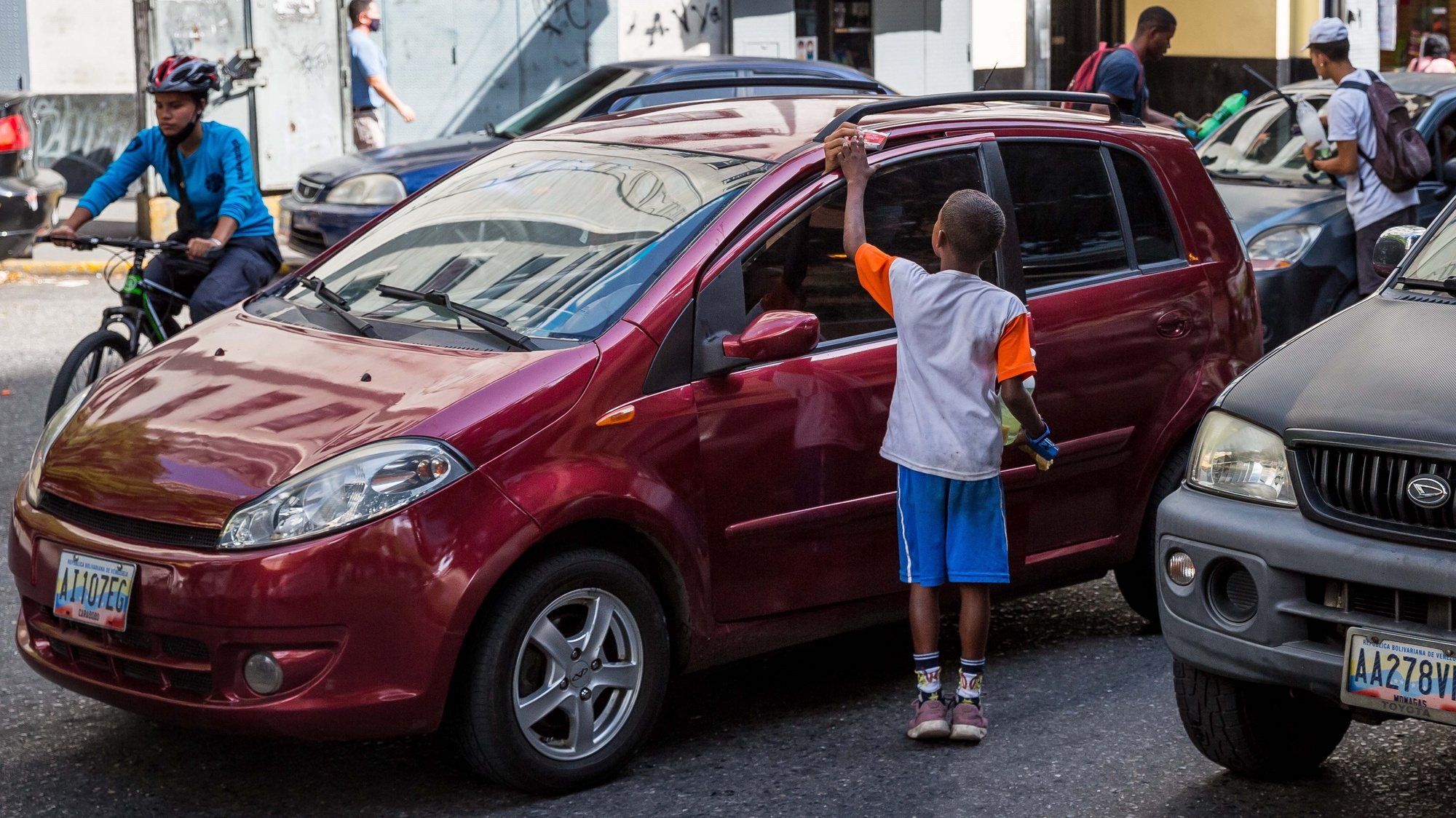 epa09522460 Several children and young people clean cars&#039; windows, on a street in Caracas, Venezuela, 06 October 2021 (Issued 13 October 2021). The lack of public policies regarding the protection of children&#039;s rights in Venezuela has resulted in the violation of the rights of minors, many of whom are forced to take to the streets to work and get their daily livelihood.  EPA/MIGUEL GUTIERREZ