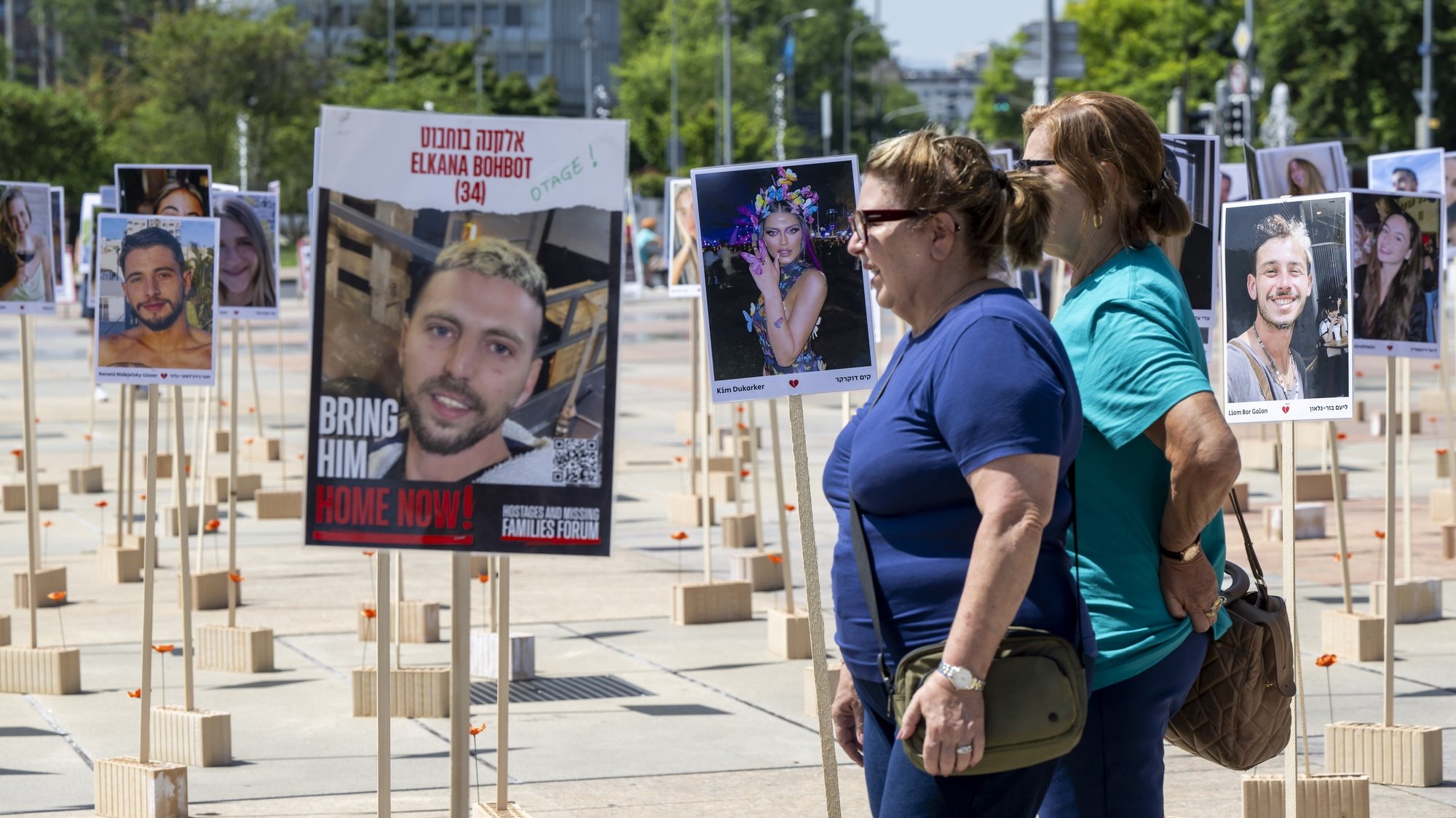 epa11422551 People look at portraits of Israeli hostages kidnapped by Hamas militants during the October 7 attacks that are installed in front of the United Nations European headquarters in Geneva, Switzerland, 19 June 2024, during the 56th session of the Human Rights Council.  EPA/MARTIAL TREZZINI