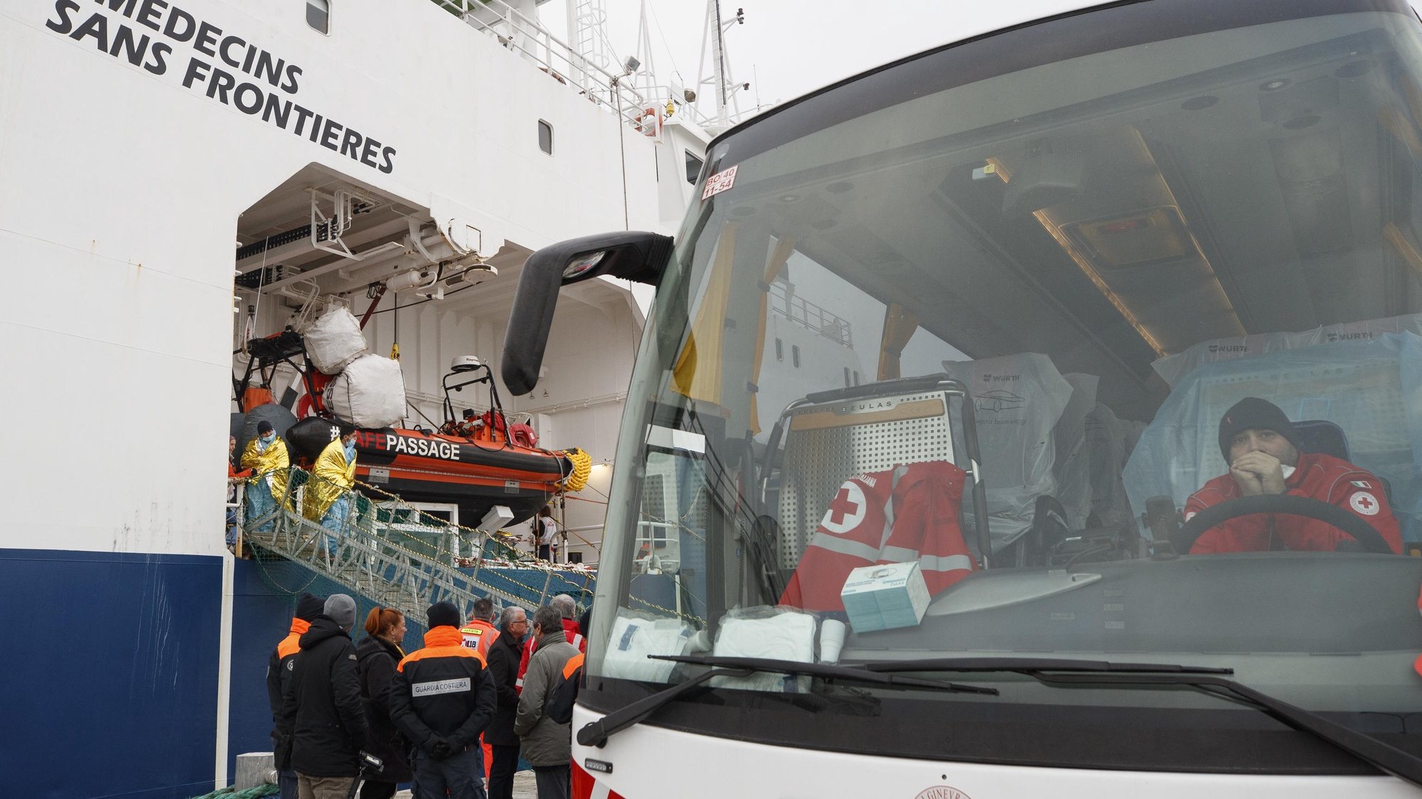 epa11054767 A bus of the Italian Red Cross (IRC) waits for migrants disembarking from the Geo Barents rescue ship, operated by Doctors Without Borders (Medecins Sans Frontieres or MSF), after it docked in the port of Ravenna, Emilia-Romagna region, northern Italy, 03 January 2024. The 336 migrants, including 34 minors, 27 of whom are unaccompanied, disembarked in Ravenna in the morning, the highest number ever recorded in Emilia-Romagna.  EPA/FABRIZIO ZANI