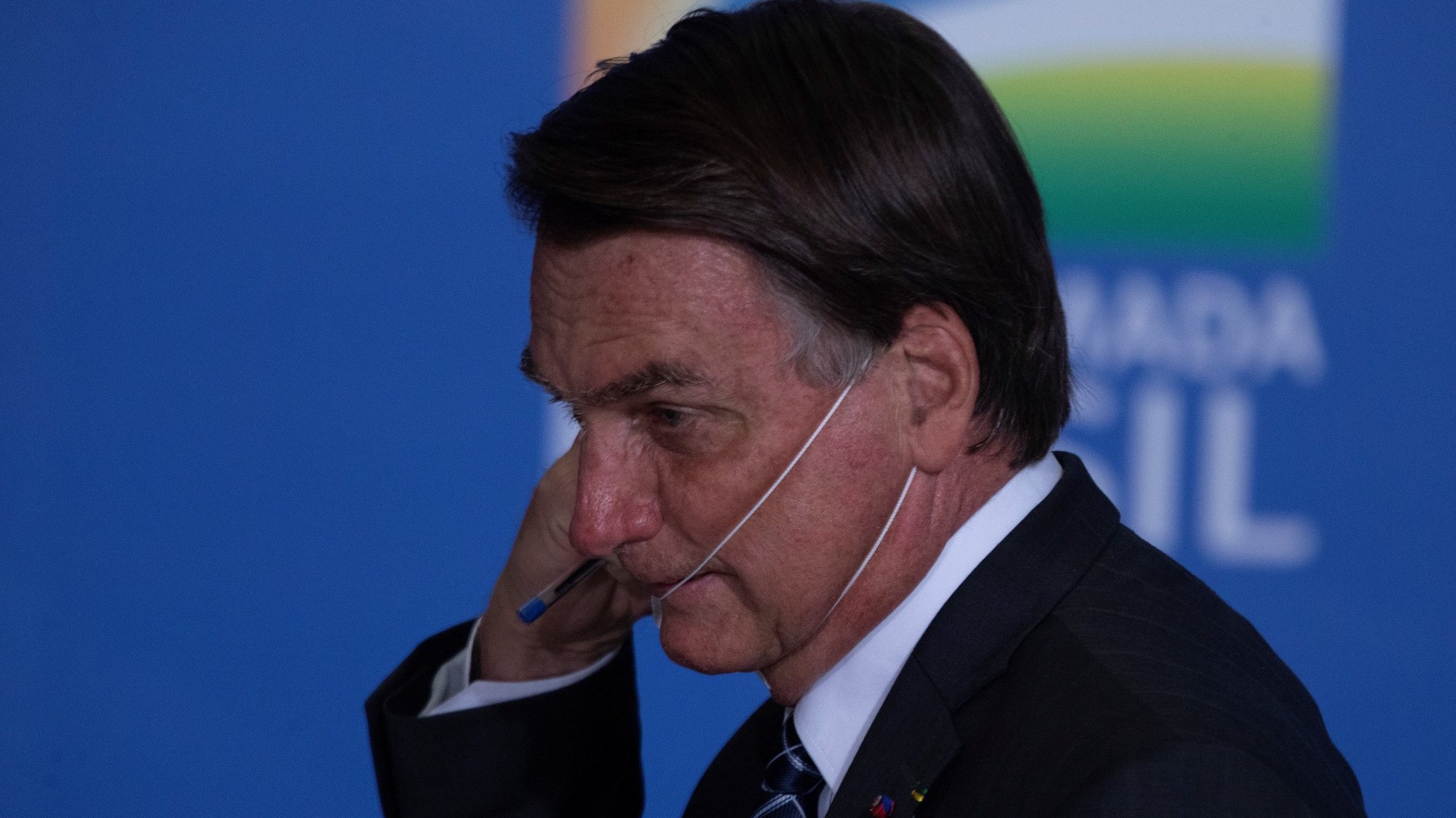 epa09294580 Brazilian President Jair Bolsonaro removes his face mask during the launching of an agriculture program at Planalto Presidential Palace in Brasilia, Brazil, 22 June 2021. Brazil&#039;s Goverment announced some US $50 billion for investments in agriculture during 2021-2022.  EPA/JoÃ©dson Alves