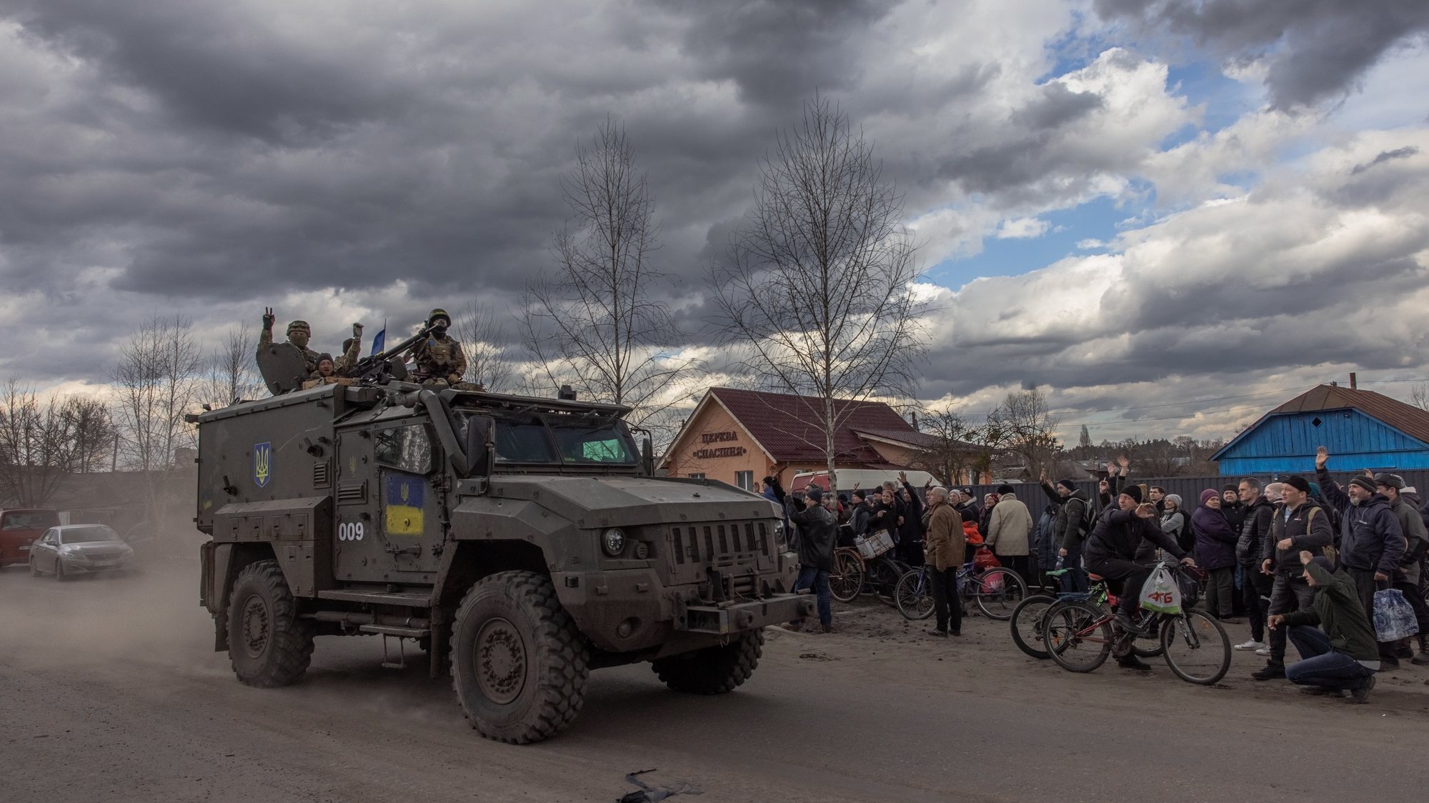 epa09859930 Ukrainian soldiers wave from a military vehicle to local residents waiting in a queue for humanitarian aid, in the recaptured by the Ukrainian army Trostyanets town, in Sumy region, Ukraine, 29 March 2022 (issued 30 March 2022). Trostyanets was recaptured by the Ukrainian army after the town was under Russian forces from the first days of war for over a month. Russian troops entered Ukraine on 24 February prompting the country&#039;s president to declare martial law and triggering a series of announcements by Western countries to impose severe economic sanctions on Russia.  EPA/ROMAN PILIPEY