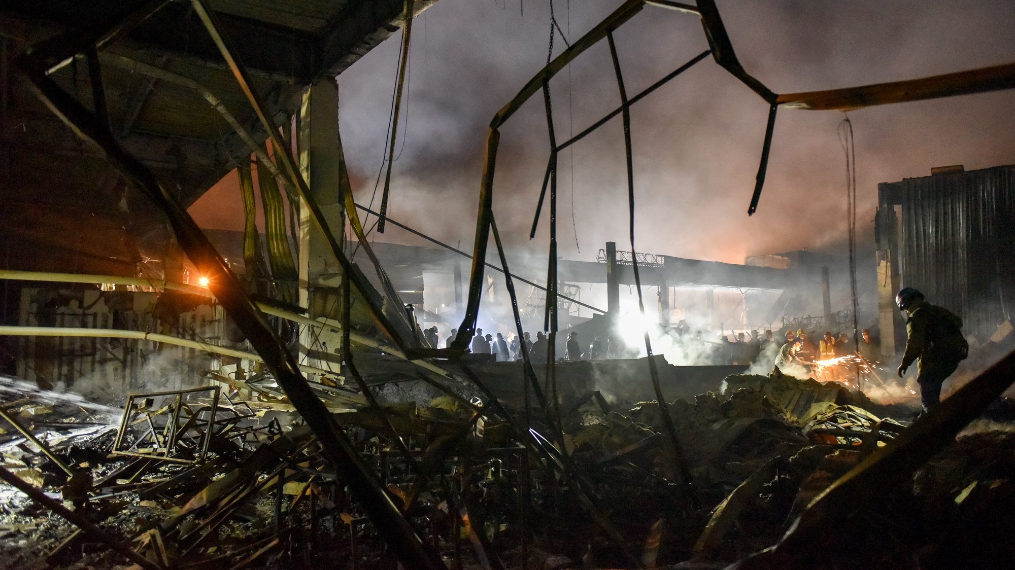 epa10037594 Firefighters clean the rubble of the destroyed Amstor shopping mall in Kremenchuk, Poltava Oblast, Ukraine, 27 June 2022. At least eleven bodies were found dead at the scene, the State Emergency Service (SES) of Ukraine said in a Telegram post, and at least 58  injured following Russian airstrikes on the crowded shopping mall. The one-story building of a shopping center was hit by Russian rockets in the afternoon.  EPA/OLEG PETRASYUK