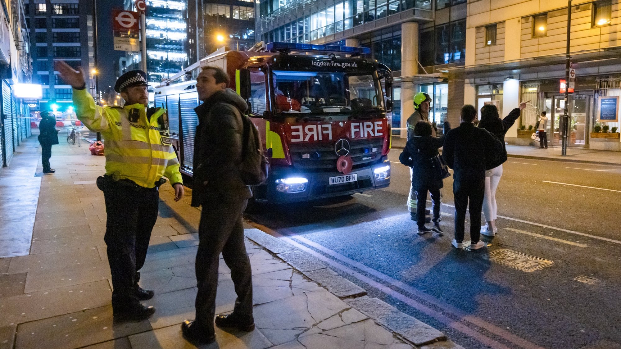 epa09808689 Police direct people around road closures near the scene of a fire which broke out in a block of flats in Whitechapel High Street in London, Britain, 07 March 2022. A fire that broke out on the 17th floor of a 21-storey building was contained after 15 engines and 125 firefighters were deployed to the scene.  EPA/VICKIE FLORES