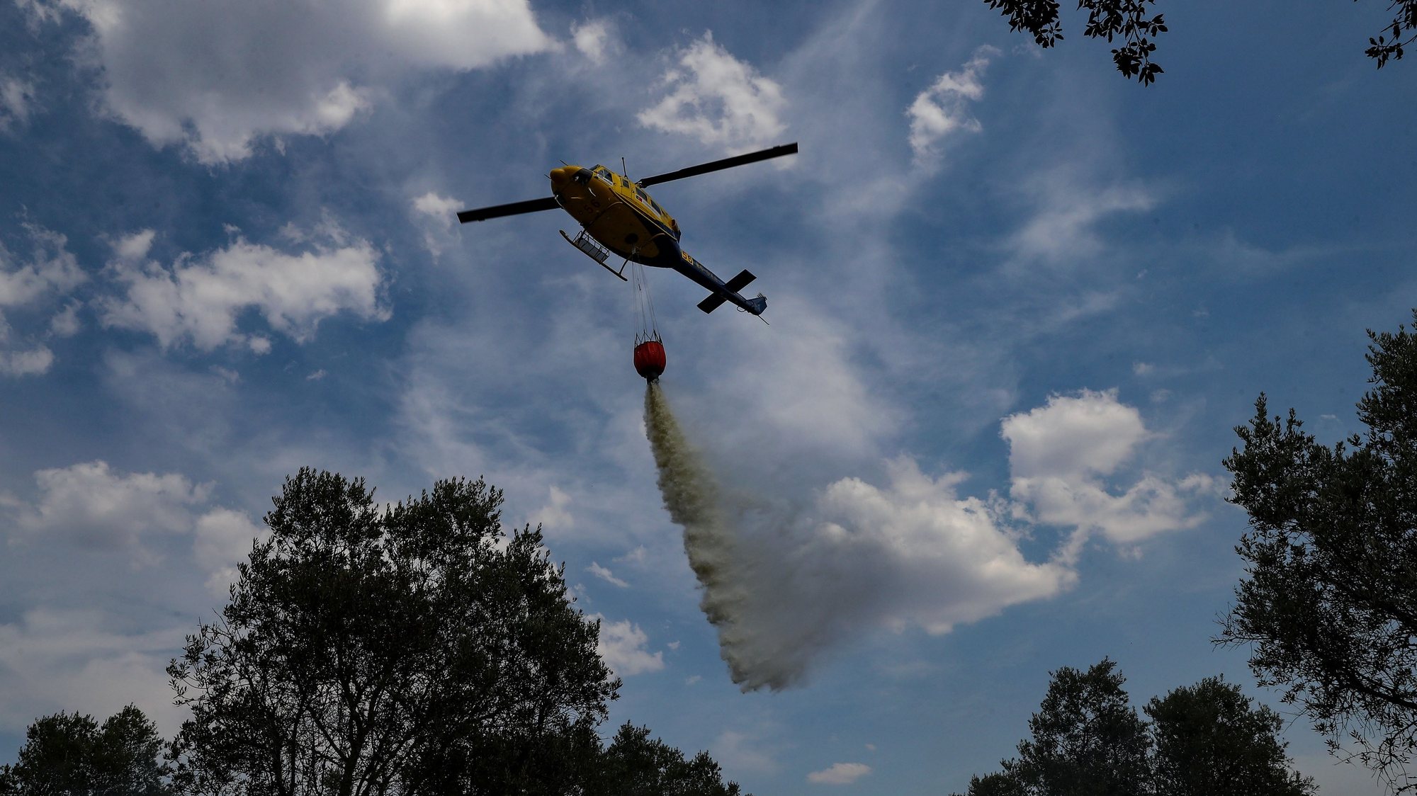 Um helicóptero apoia os meios terrestres no combate a um incêndio rural rapidamente controlado por populares, bombeiros e uma equipa da Unidade de Emergência de Proteção e Socorro (UEPS) da GNR, na freguesia de Santiago do Escoural, Montemor-o-Novo, 11 de julho de 2022. NUNO VEIGA/LUSA