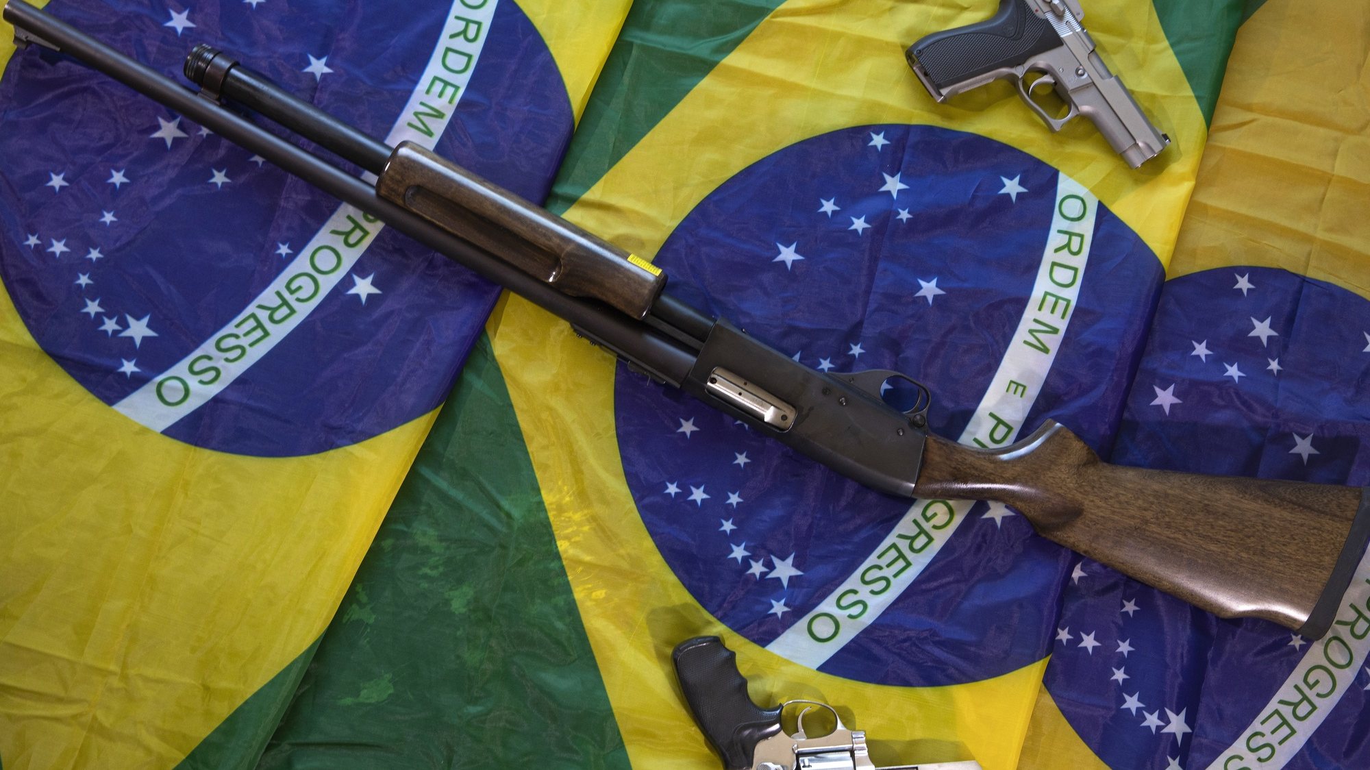 epa10161718 Photograph of the three firearms used by a 65-year-old man for his personal security, on Brazilian flags in Brasilia, Brazil, 25 August 2022 (issued 05 September 2022). The number of armed civilians in Brazil has increased by 473% since the far-right Jair Bolsonaro came to power in January 2019, and the matter worries the electoral authorities ahead of the 02 October presidential elections.  EPA/Joedson Alves