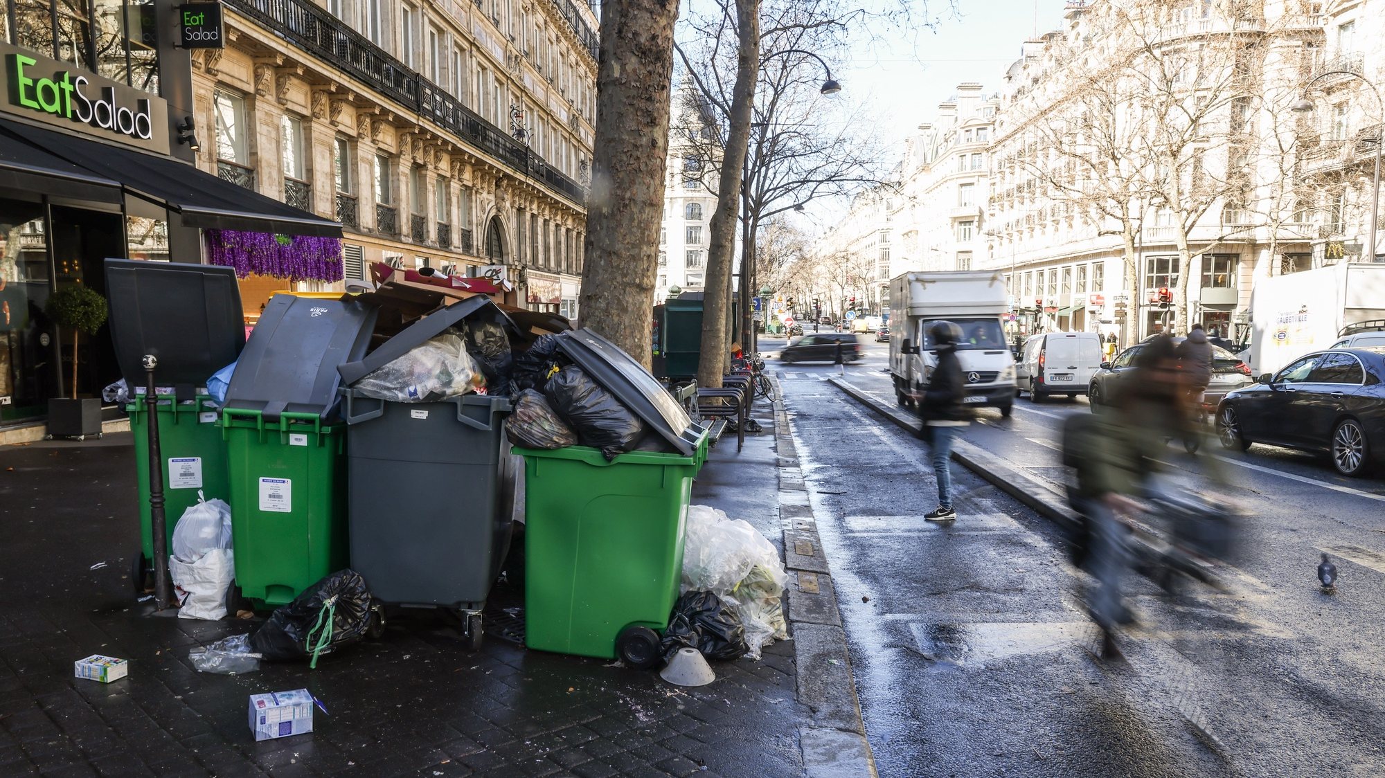 epa10522118 People pass by next to garbage cans overflowing with trash in Paris, France, 14 March 2023. Garbage collectors have joined the massive strikes in France against the government&#039;s pension reform plans, piling the streets of the French capital in the meantime with thousands of tonnes of garbage.  EPA/Mohammed Badra