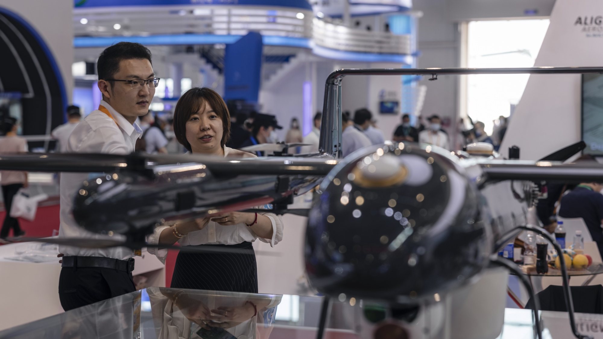 epa09492562 People look at an unmanned aerial vehicle (UAV) during the 13th China International Aviation and Aerospace Exhibition in Zhuhai, Guangdong province, China, 28 September 2021. The event, also known as Airshow China, runs from 28 September through 03 October 2021. According to military commentator Song Zhongping&#039;s statement to the media, the exhibition presents sophisticated surveillance drones and jets able to jam electronic equipment with a focus on disputed territories from Taiwan to the South China Sea. Airshow China has become one of the top five air shows in the world.  EPA/ALEX PLAVEVSKI