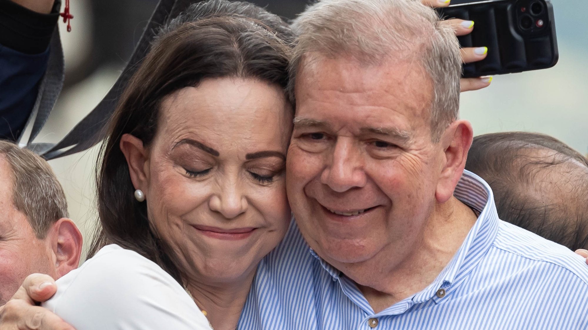 epaselect epa11510252 Venezuelan opposition leader Maria Corina Machado (L) hugs Venezuelan presidential candidate Edmundo Gonzalez Urrutia at a rally in Caracas, Venezuela, 30 July 2024. Thousands of Venezuelans gathered in Caracas on 30 July in an event called by the majority opposition, to reject for the second consecutive day what they consider to be fraud in the official results of the National Electoral Council (CNE), which proclaimed Nicolas Maduro as re-elected president with 51.2 percent of the votes.  EPA/RONALD PENA R