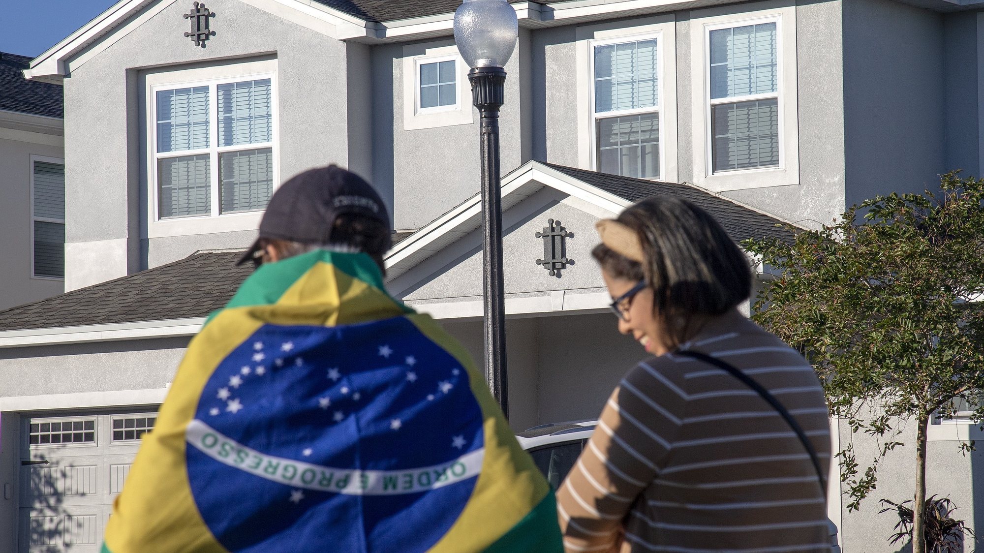 epa10401534 People stand in front of the house at the Encore Resort Homes, where former Brazil president Jair Bolsonaro is staying, in Reunion, Florida, USA, 12 January 2023. US Lawmakers called US President Joe Biden to extradite Bolsonaro back to his country from Florida. Bolsonaro has been staying in Central Florida, near Orlando, as his supporters protest in Brazil.  EPA/CRISTOBAL HERRERA-ULASHKEVICH