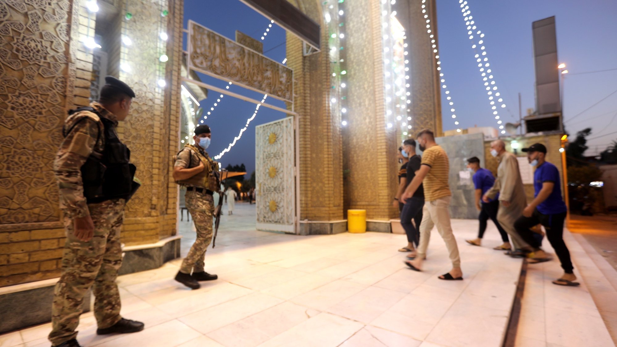 epa09354337 Iraqi policemen stand guard as Iraqi Sunni Muslims arrive to perform Eid Al-Adha prayers amid the COVID-19 pandemic at the  Abu Hanifa mosque in Baghdad&#039;s Adhamiya district, Iraq, 20 July 2021. Eid al-Adha is the holier of the two Muslims holidays celebrated each year; it marks the yearly Muslim pilgrimage (Hajj) to visit Mecca, the holiest place in Islam. Muslims slaughter a sacrificial animal and split the meat into three parts, one for the family, one for friends and relatives, and one for the poor and needy.  EPA/AHMED JALIL
