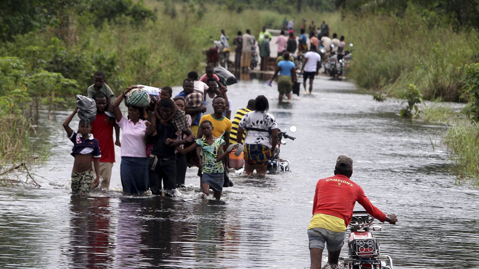epa03429135 Nigerians move along a flooded road in Okpe, Isoko north local goverment council Niger delta, Nigeria, 11 October 2012. Heavy rains over over the past weeks have caused devastating floods which have submerged most communities in the oil rich Niger delta region of Nigeria.  EPA/GEORGE ESIRI
