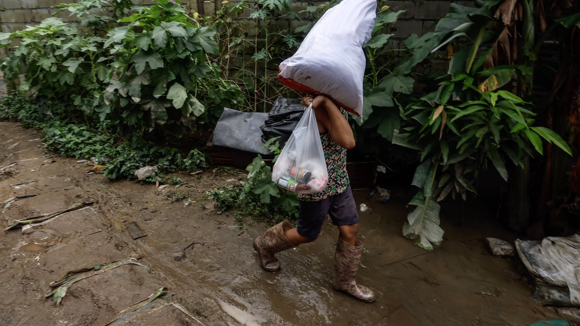epa10772853 A boy carries belongings and relief food while walking along a path muddied with flood water due to the effects of typhoon Doksuri in San Mateo village, northeast of Manila, Philippines, 28 July 2023. According to the National Disaster Risk Reduction and Management Council (NDRRMC), around 500,000 people or approximately 140,000 families were affected by the onslaught of heavy rains and strong winds caused by typhoon Doksuri which moved out of Philippine seas on 27 July. Damage to infrastructure was estimated to be 656-million pesos (10.9 million euro) and damage to the agriculture sector was 62-million pesos (1.03 million euro).  EPA/ROLEX DELA PENA