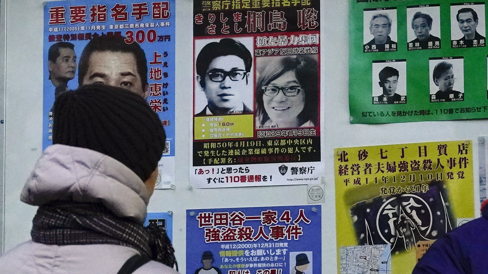 epa11110518 Pedestrians look at wanted poster of a man (C-Top), the suspect on a wanted list for one of terrorist bombings in the 1970s, displayed at Tokyo Metropolitan Police Department in Tokyo, Japan, 28 January 2024. Tokyo police said a man is being questioned by Tokyo Metropolitan Police Department&#039;s Public Safety Department from early January 2024, believed to be Satoshi Kirishima, 70, a suspect responsible for one of terrorist bombings in the 1970s. The man has been hospitalized under false name in Kanagawa Prefecture, south of Tokyo, for receiving treatment for terminal cancer, according to investigative authorities on 27 January 2024. The Tokyo police is now investigating the identity of the man believed to be the 50-year-long fugitive criminal.  EPA/KIMIMASA MAYAMA