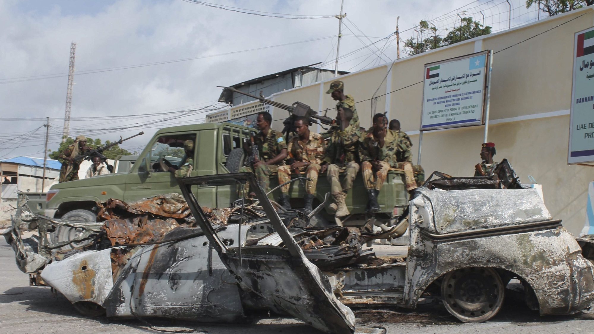 epa04306955 Somali troops sit in the back of a pickup truck in front of a wreckage of a car that exploded at the gate of the presidential palace in Mogadishu, Somalia, 09 July 2014, where gunmen from the militant group al-Shabab attacked the night before. Militants stormed into the compound detonating a car bomb and firing shots on late 08 July, in an attempt to take control of the buildings inside. President Hassan Sheikh Mohamud was not inside the palace at the time of attack. Somali security officers and African Union troops thwarted attacks after exchanging gunfire. Three attackers were killed and one was captured, said the presidential office in a statement.  EPA/SAID YUSUF WARSAME