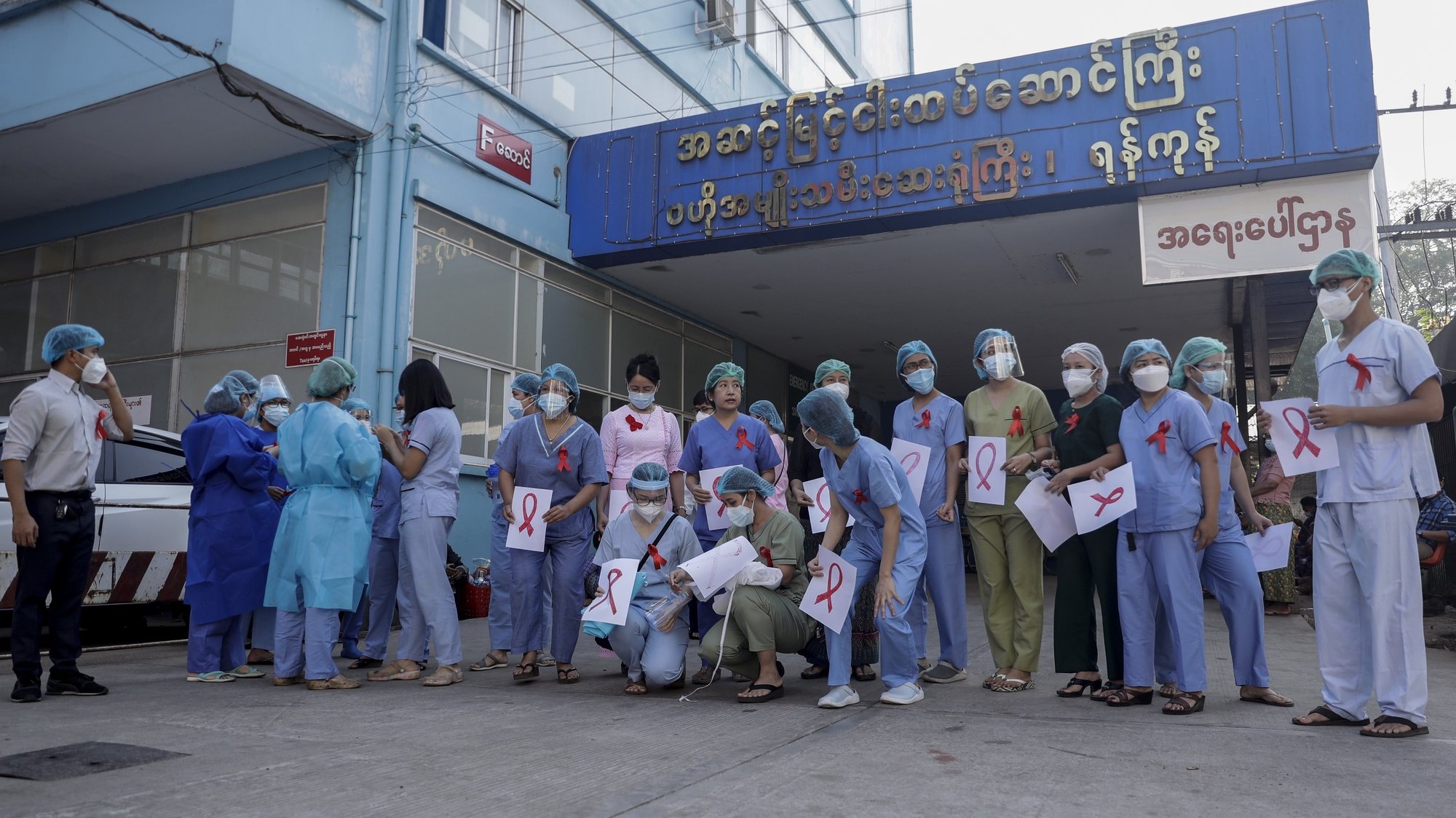 epa08983139 Medical workers wearing red ribbons hold the placards with the sign of red ribbon as a symbol of resistance against the military coup as they prepare for a group photograph at Central Women&#039;s Hospital in Yangon, Myanmar, 03 February 2021. Medical workers are participating in a nationwide strike as part of a civil disobedience campaign protesting against the recent military coup. Myanmar’s military seized power and declared a state of emergency for one year after arresting State Counselor Aung San Suu Kyi and Myanmar president Win Myint in an early morning raid on 01 February, following increasing tension over the result of last November&#039;s parliamentary elections.  EPA/LYNN BO BO