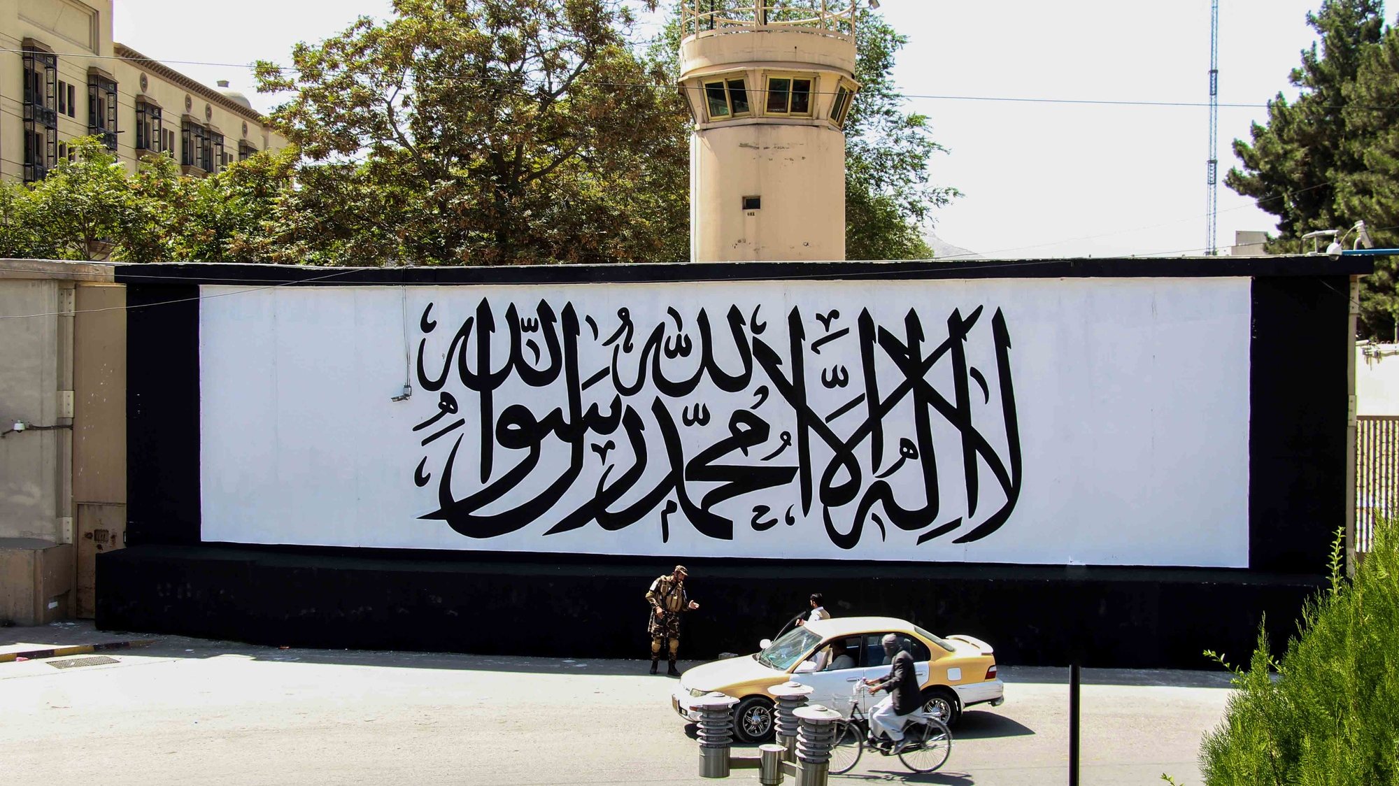 epa09455301 Taliban stand guard outside the building of former US embassy as the wall painted with text in Arabic &quot;There is not God but Allah, Muhammad is the messenger of Allah&#039; in Kabul, Afghanistan, 08 September 2021. Hundreds of protesters on 08 September, came out on the streets of cities across Afghanistan to demand their rights, a day after the Taliban officially announced the formation of a new government consisting exclusively of fundamentalists from their ranks.  EPA/STRINGER