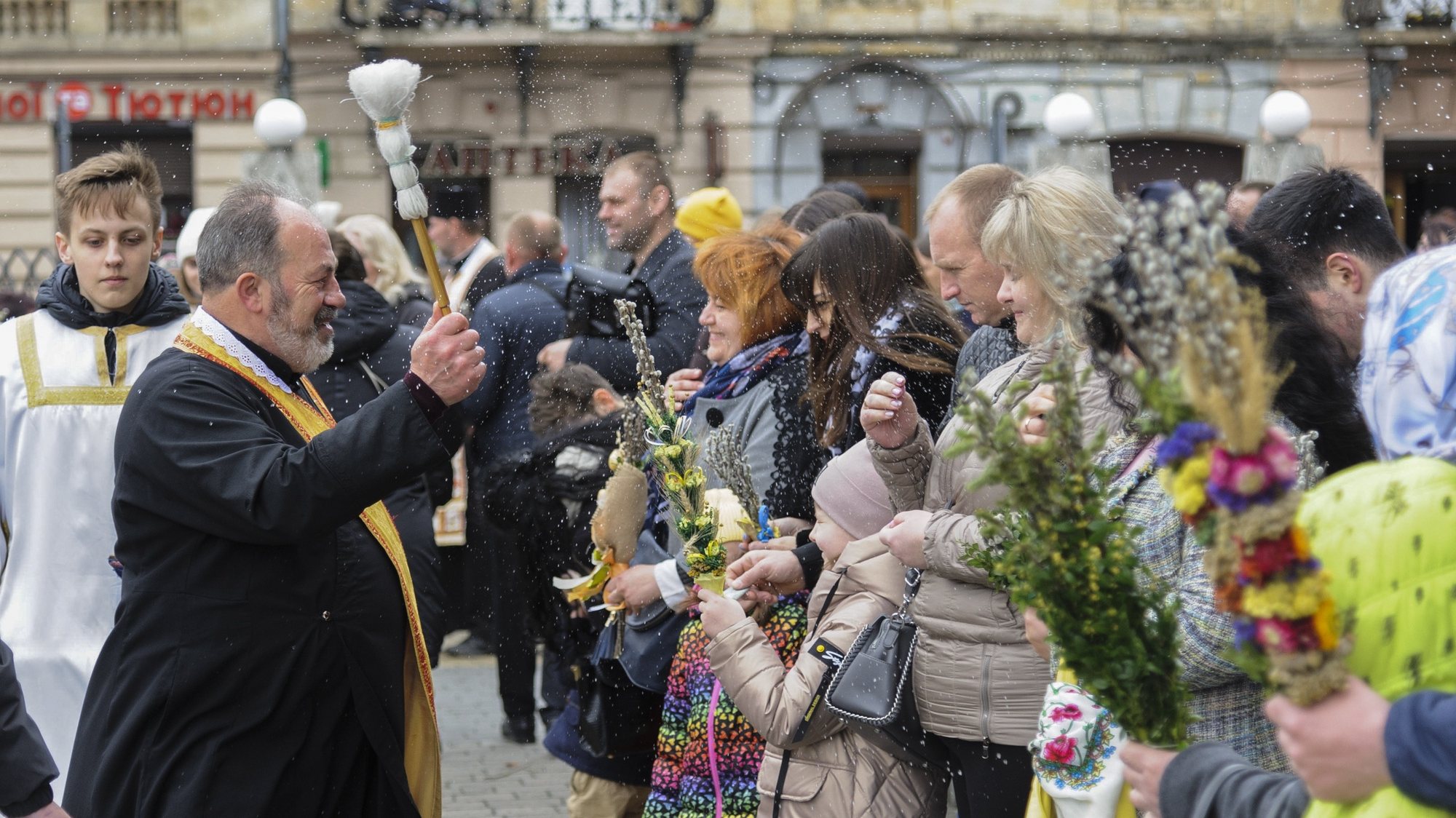 epa09894480 A Christian Orthodox priest blesses Ukrainian believers who hold pussy-willow branches as they celebrate Palm Sunday in the Western Ukrainian city of Lviv, 17 April 2022, amid the Russian invasion. Palm Sunday is the first day of Holy Week and the Sunday before Easter, commemorating the Entrance of the Jesus Christ’s into Jerusalem. Russian troops entered Ukraine on 24 February resulting in fighting and destruction in the country and triggering a series of severe economic sanctions on Russia by Western countries.  EPA/MYKOLA TYS